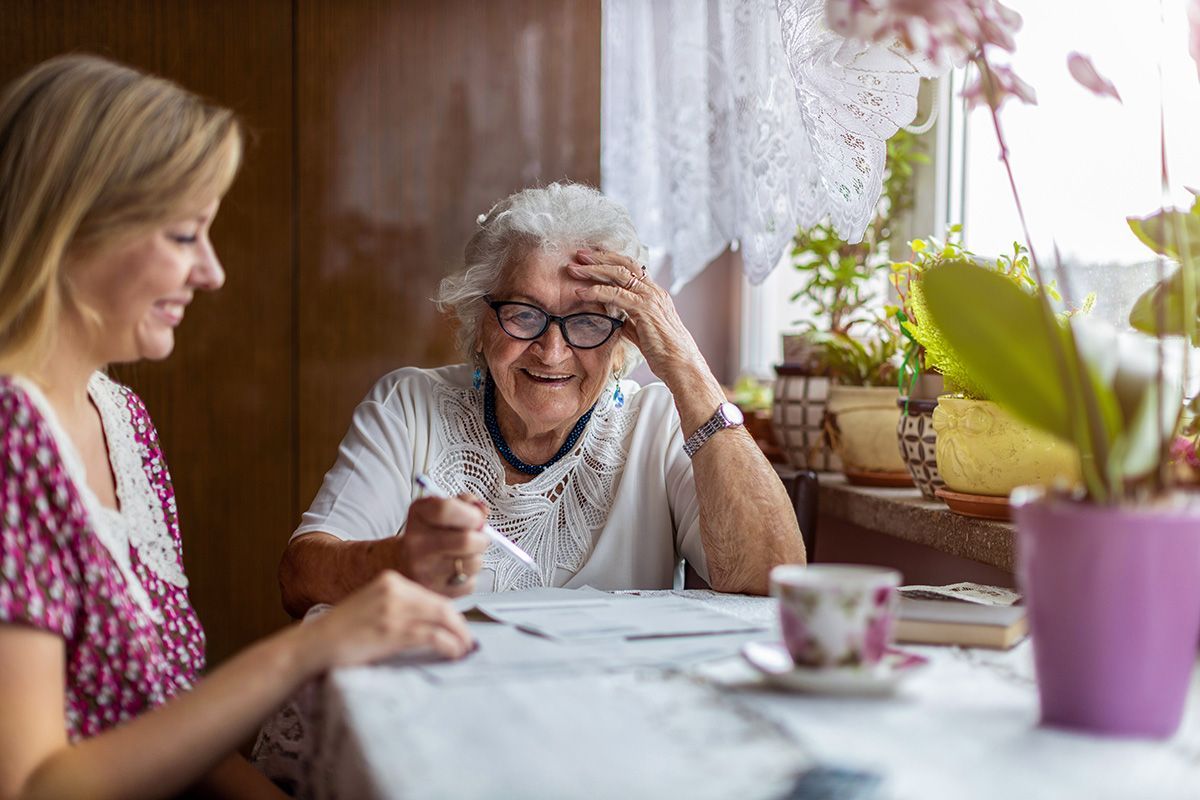 An elderly woman is sitting at a table with her carer.