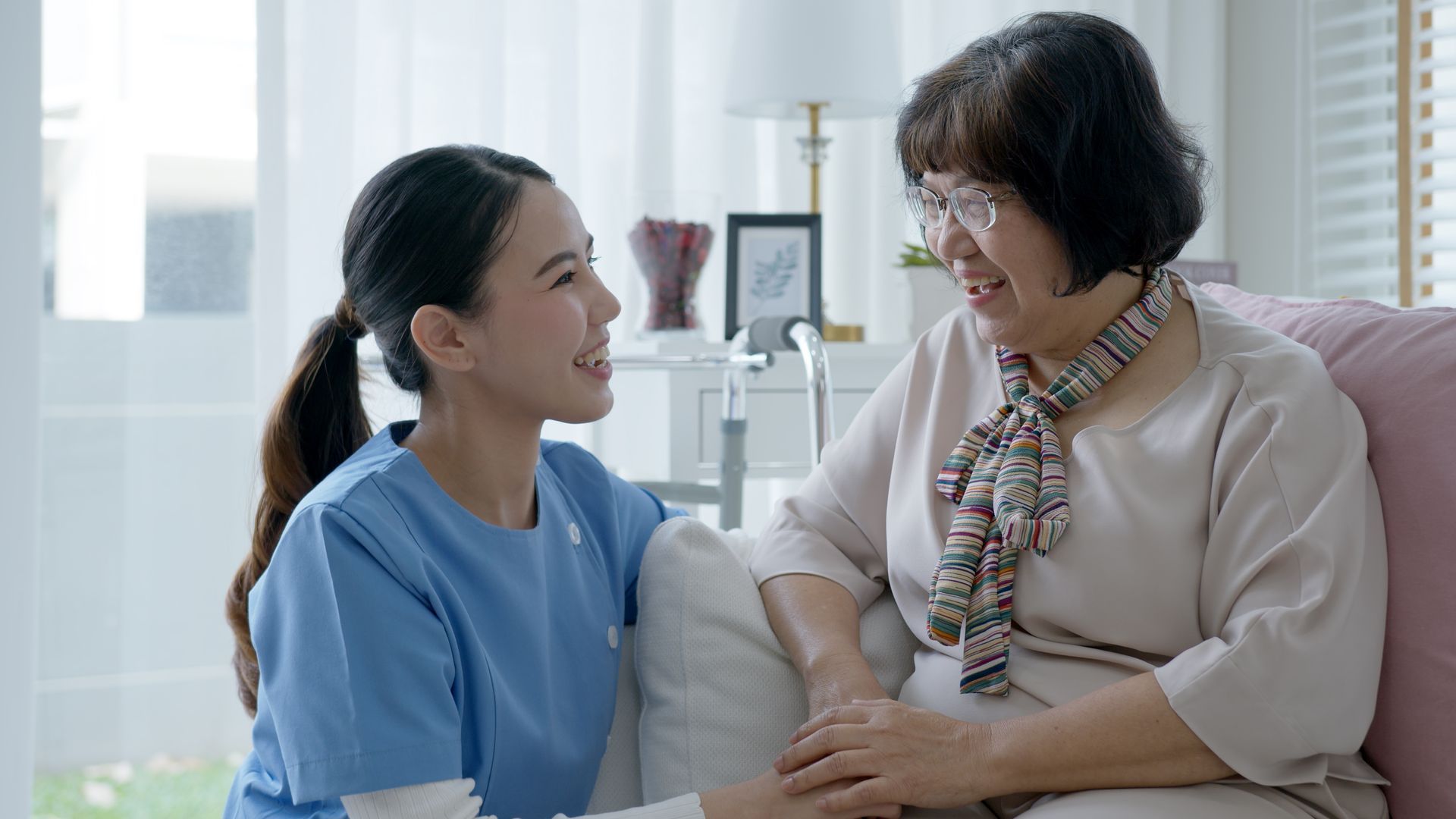 A nurse is talking to an elderly woman who is sitting on a couch.