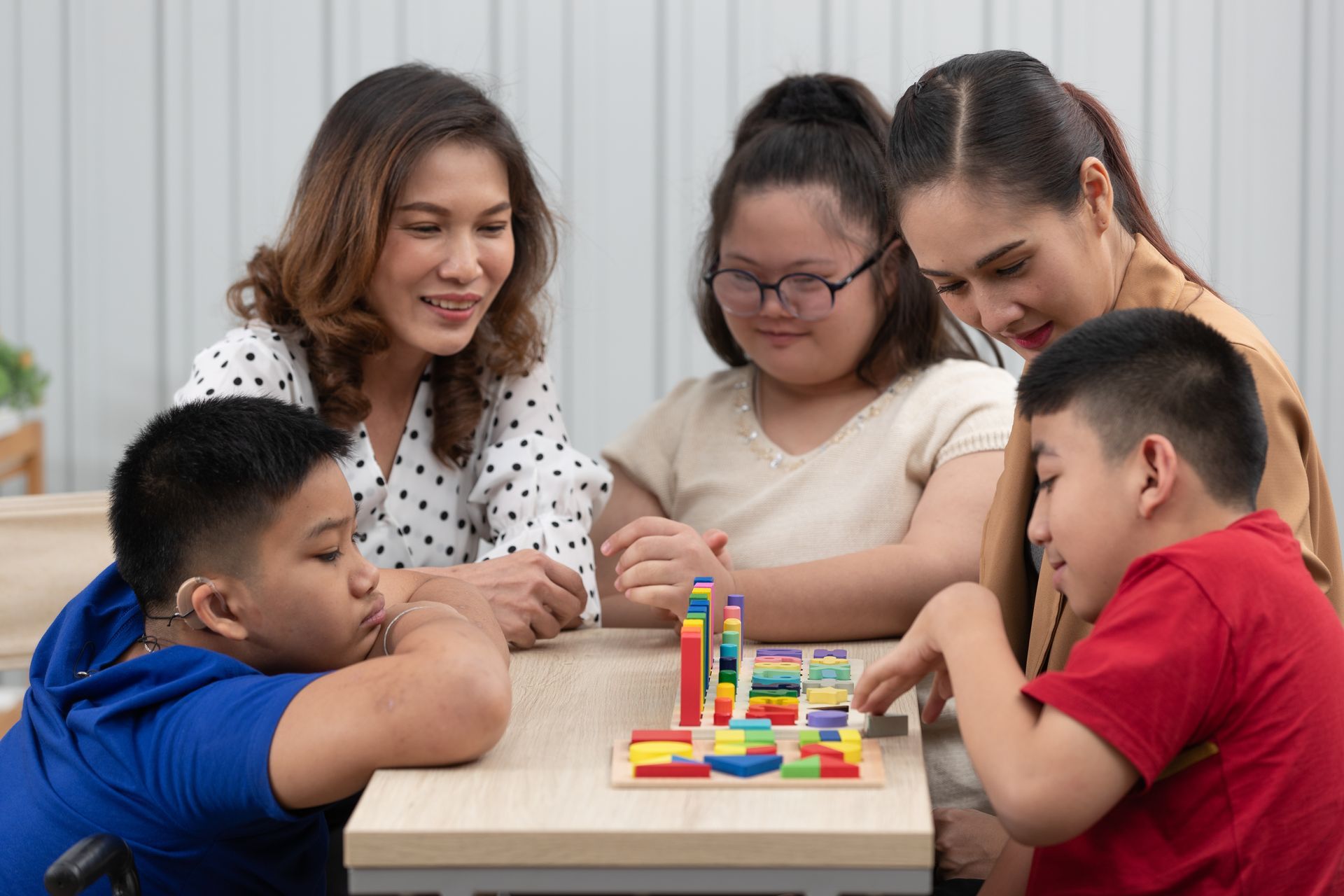 a group of moms with their children are sitting around a table playing with blocks