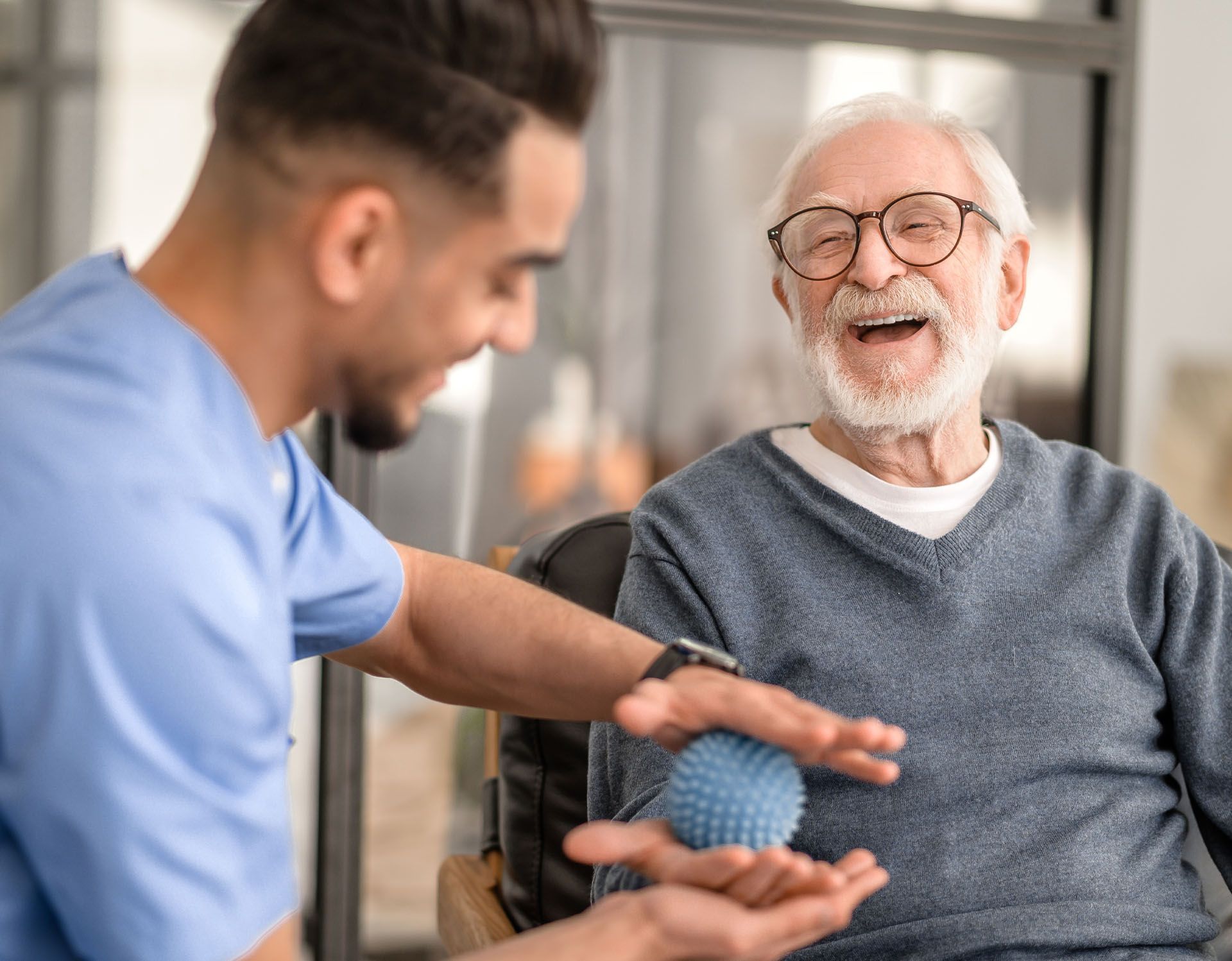 A nurse is helping an elderly man with a ball