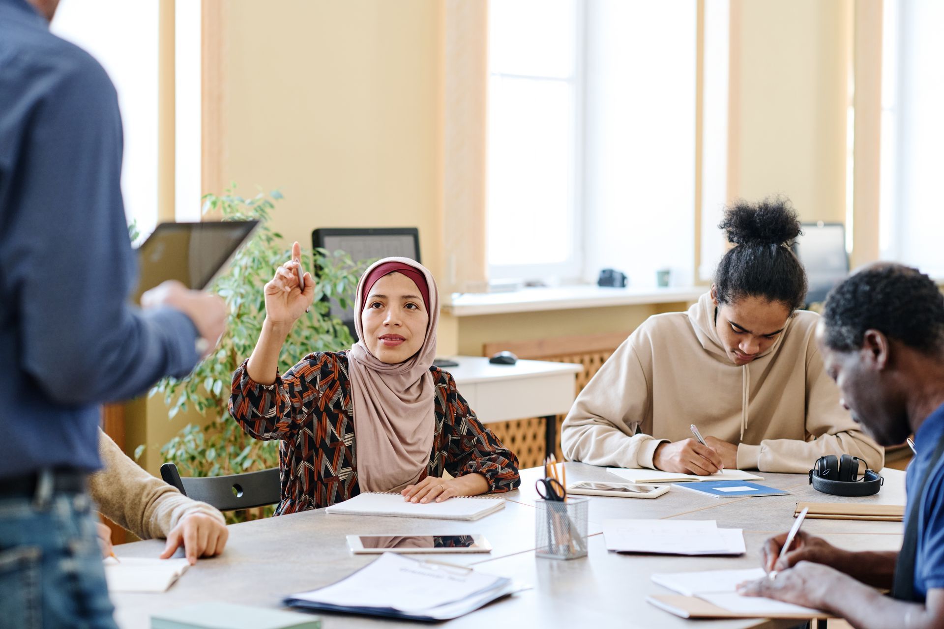 A group of people are sitting around a table in a classroom.