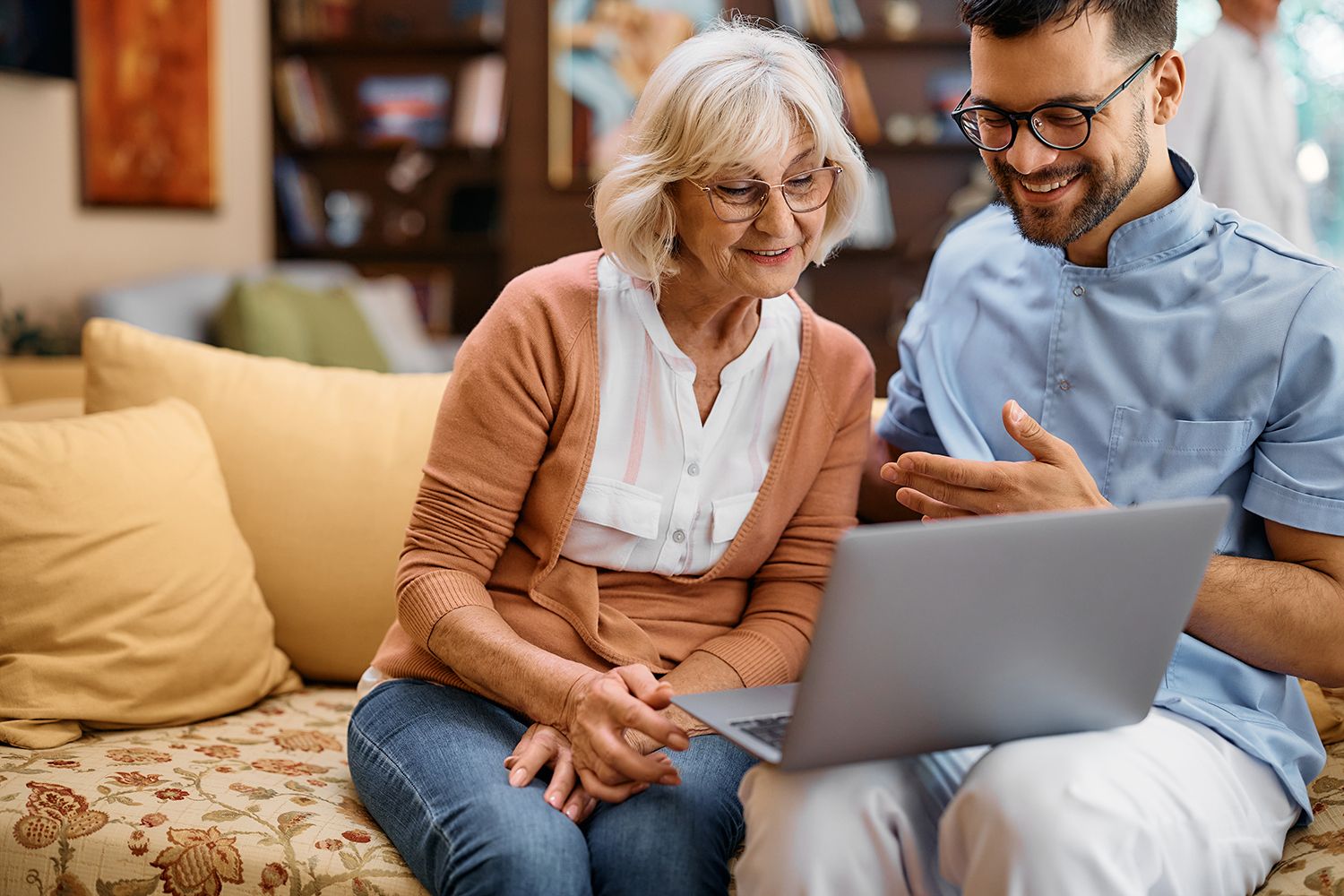 A man and a woman are sitting on a couch looking at a laptop.