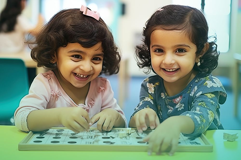 two little girls are sitting at a table playing with a puzzle
