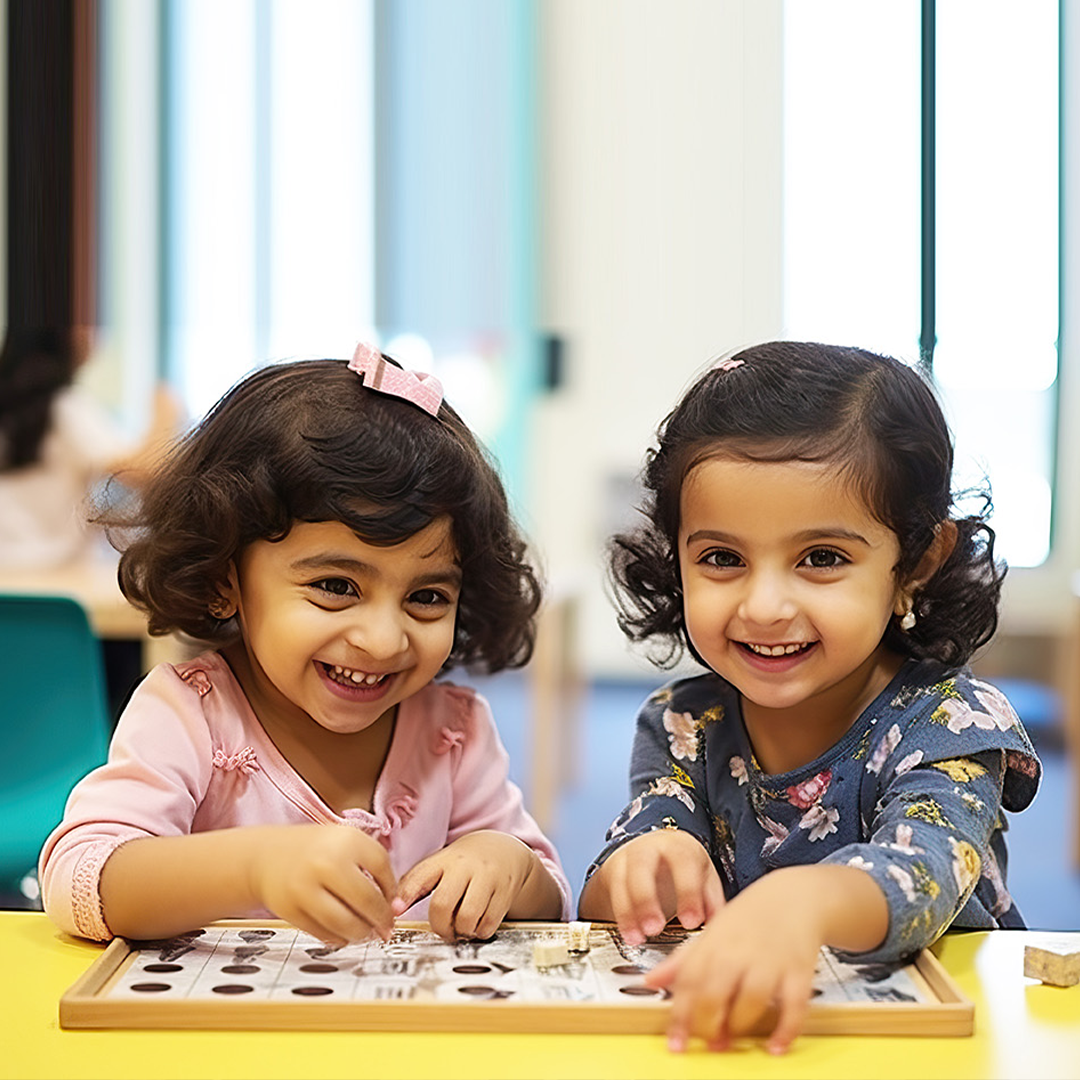 Two little girls are sitting at a table playing a game.