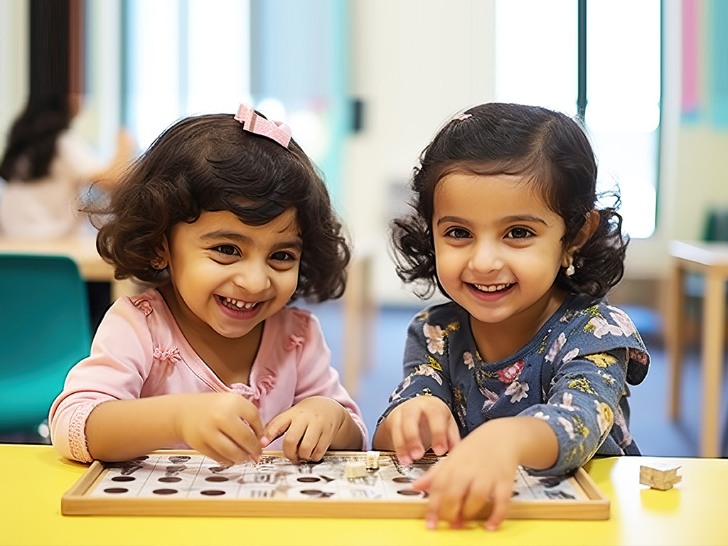 Two little girls are sitting at a table playing with a puzzle.