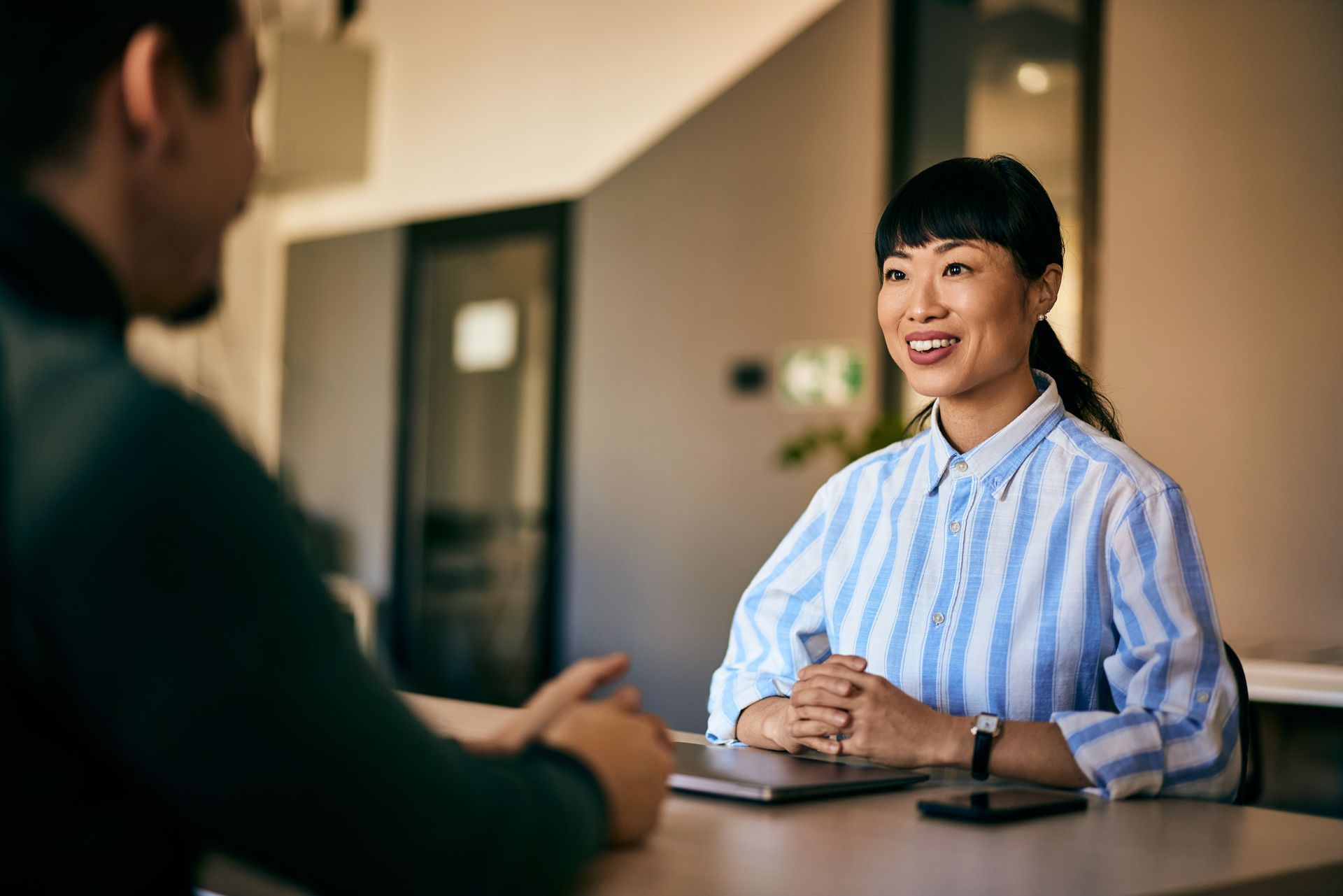 A woman is sitting at a table talking to a man.