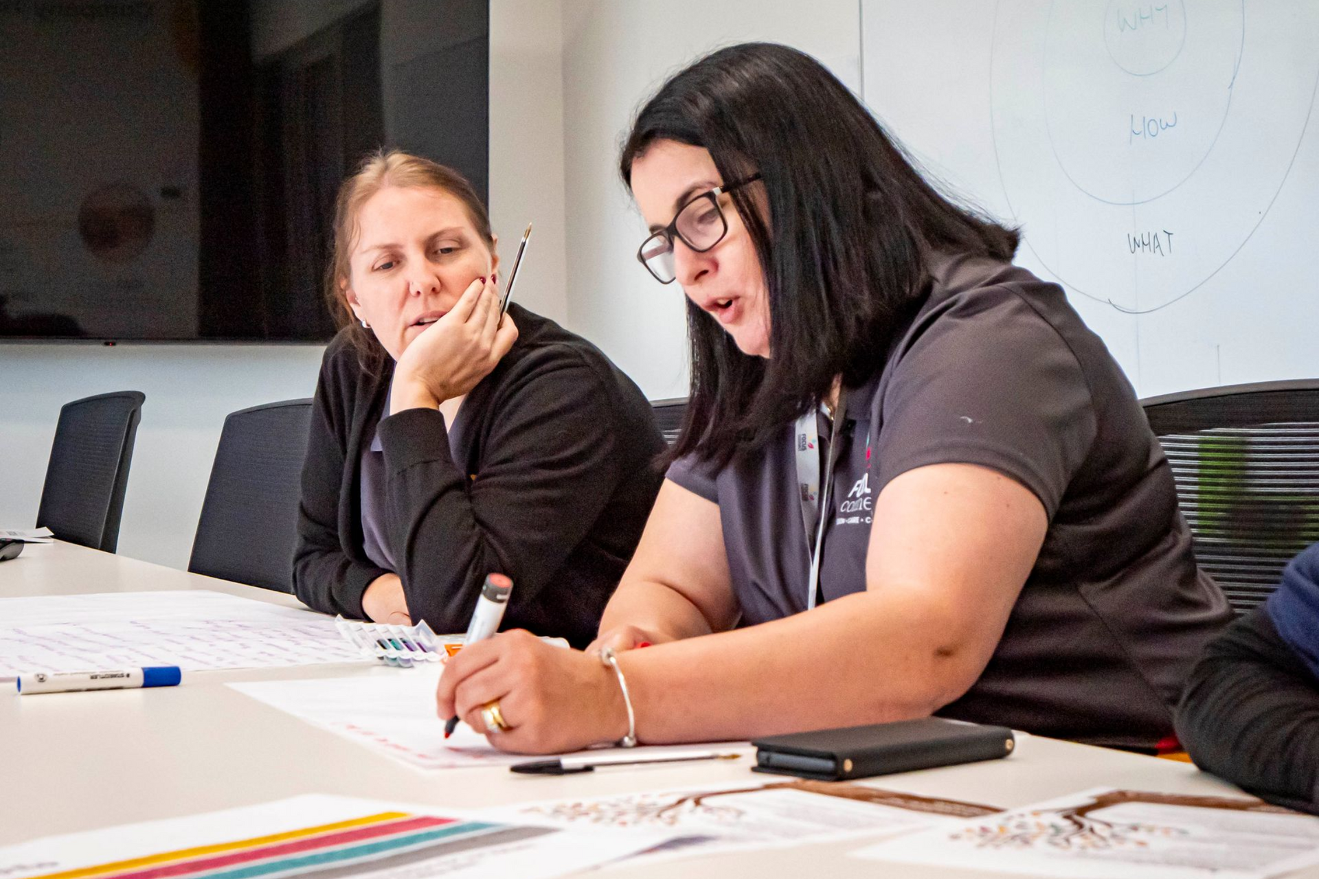 A woman is holding the hand of an elderly woman who is laying in a chair.
