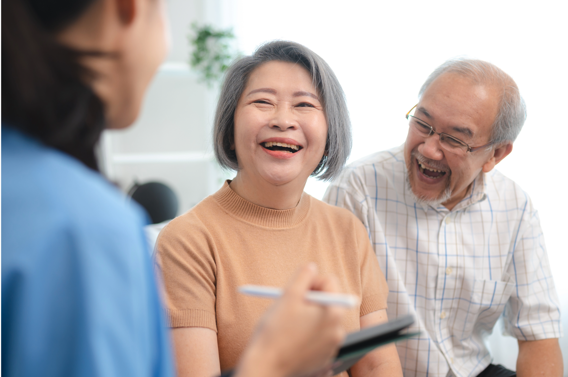 Smiling senior shaking hands with another person, sitting on a couch.