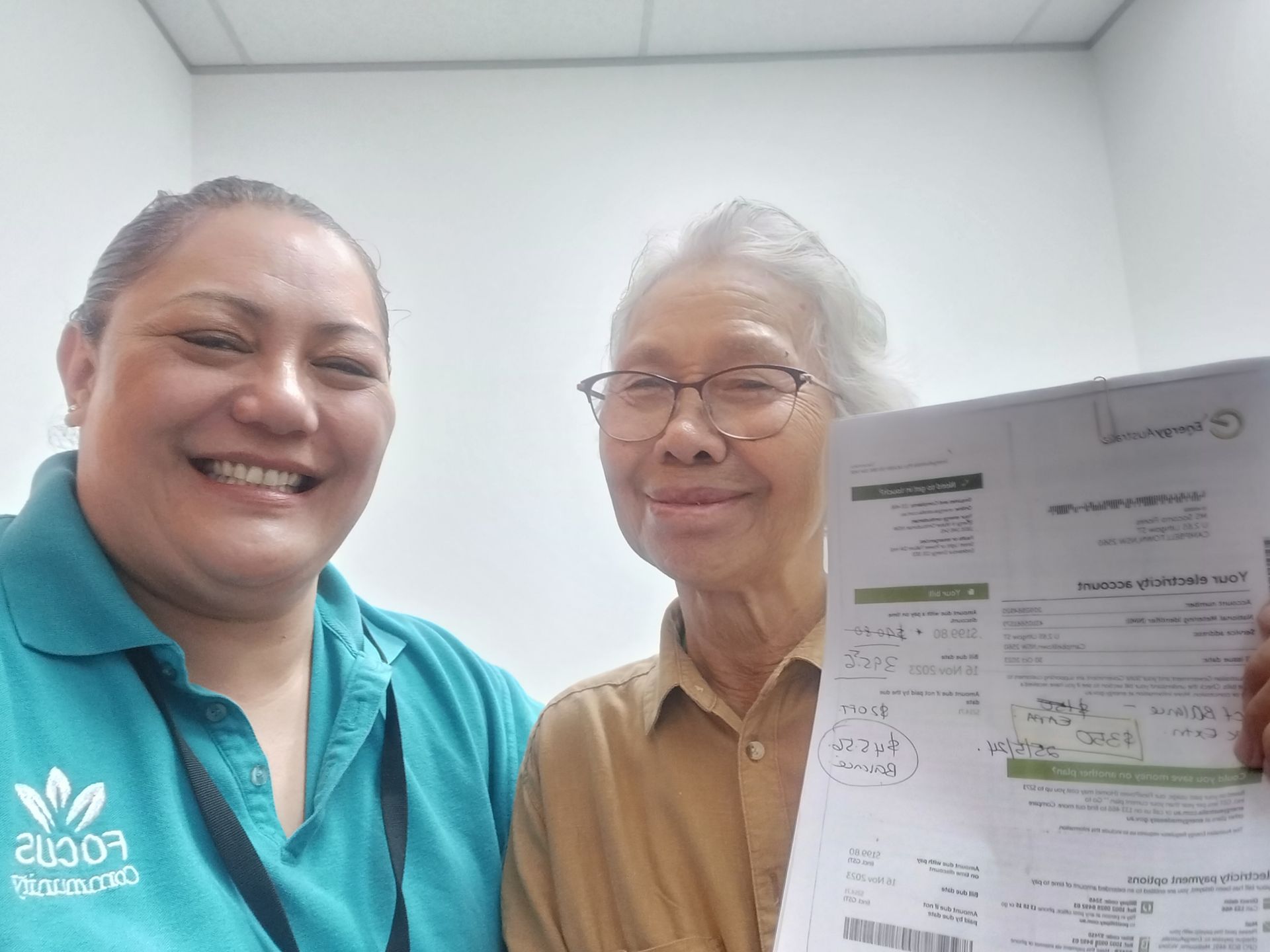 Two women are smiling and holding a piece of paper.