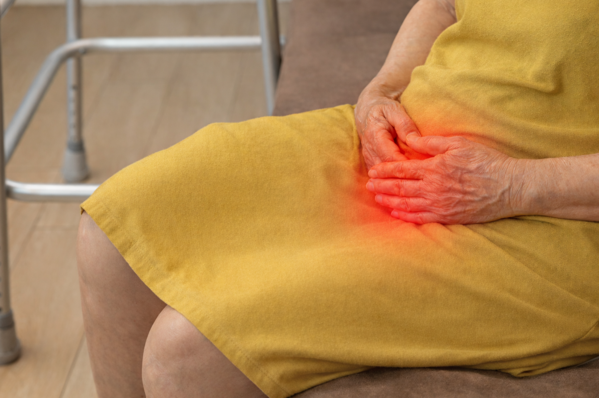 Woman seated, holding abdomen, indicated bladder pain. Yellow dress, red glow highlights area.