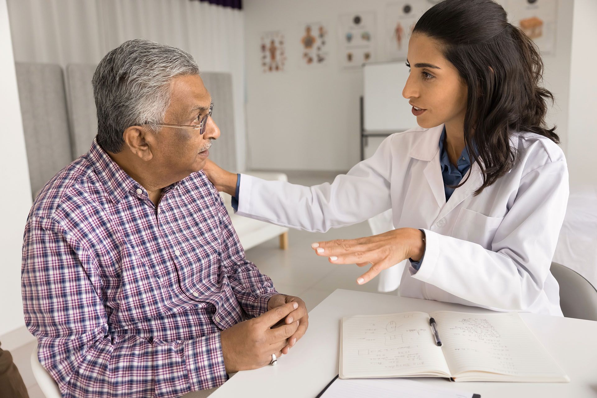 A doctor is talking to an multicultural elderly man at a table about health issues