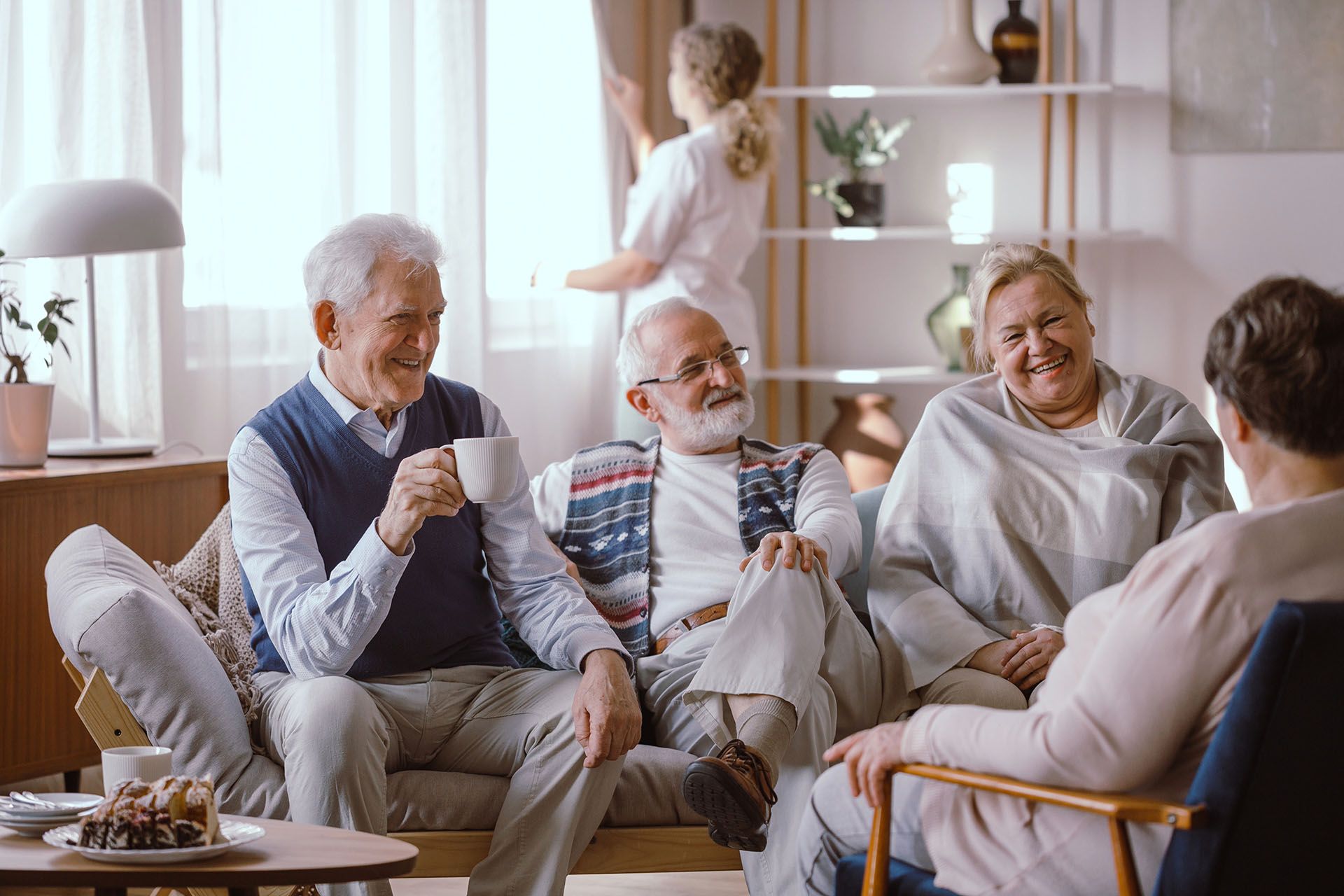 A group of elderly people are sitting on a couch talking to each other.