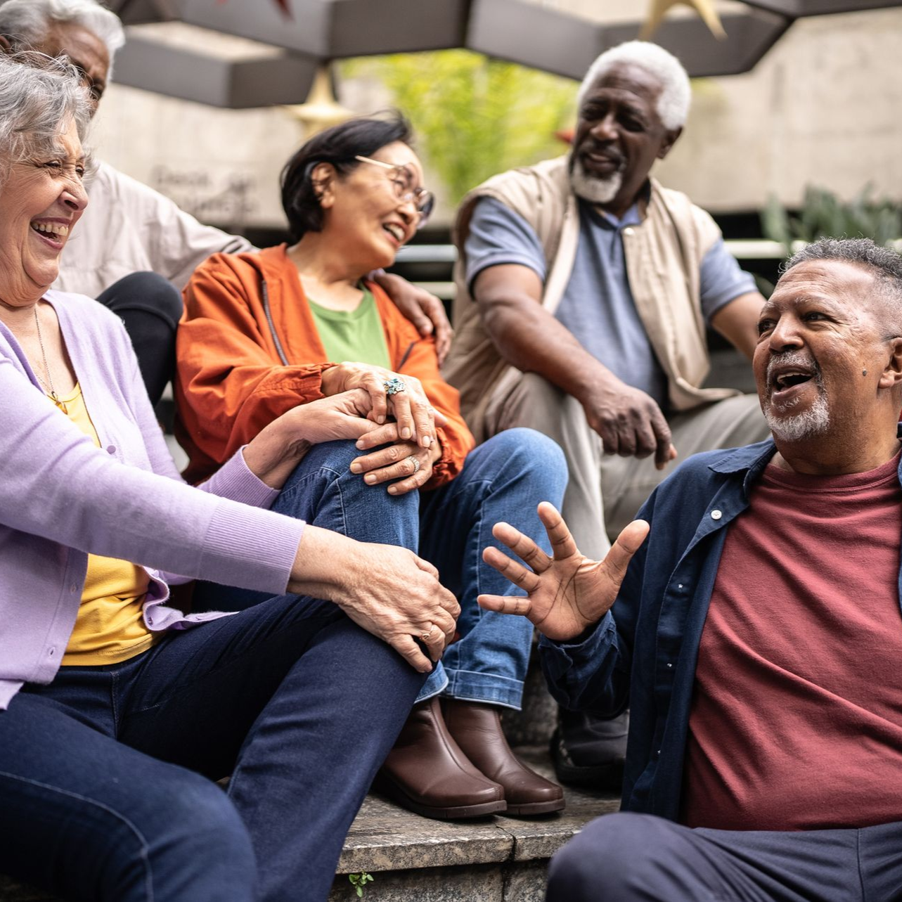 Group of people laughing and talking while sitting on outdoor steps.