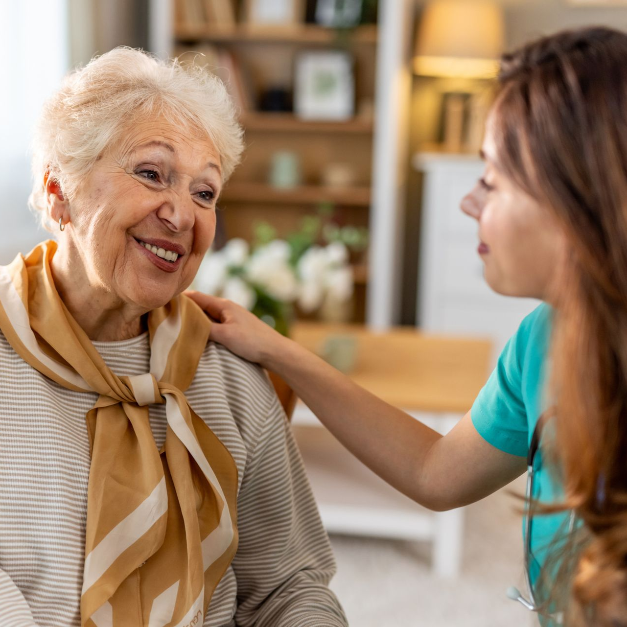 Elderly couple laughing outside, wearing glasses. Man has a white beard. Woman has silver hair.