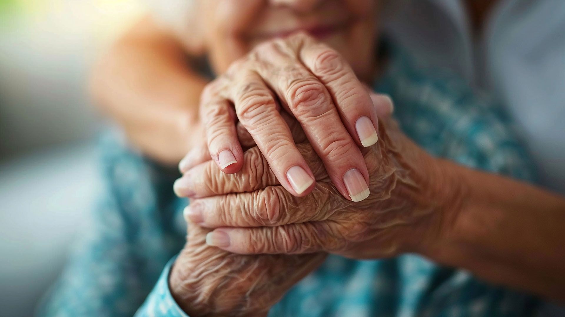 A woman is holding the hands of an elderly woman.