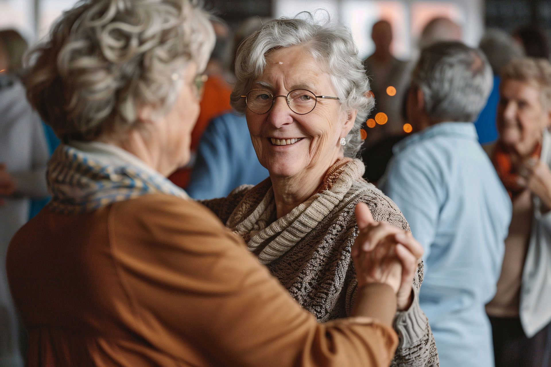 Two elderly women are dancing together in a crowd of people.