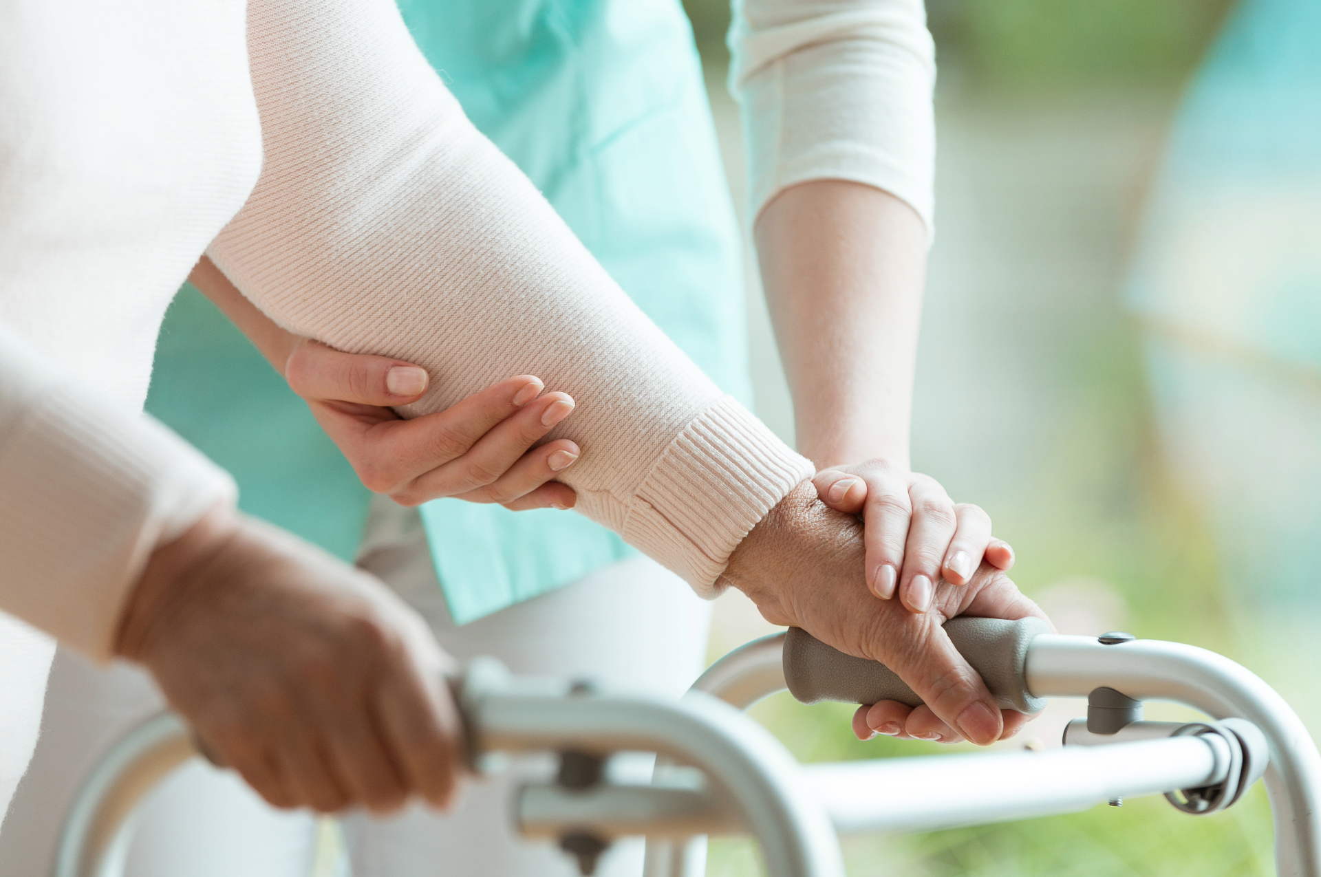 Person with walker is helped by a second person, likely indoors.