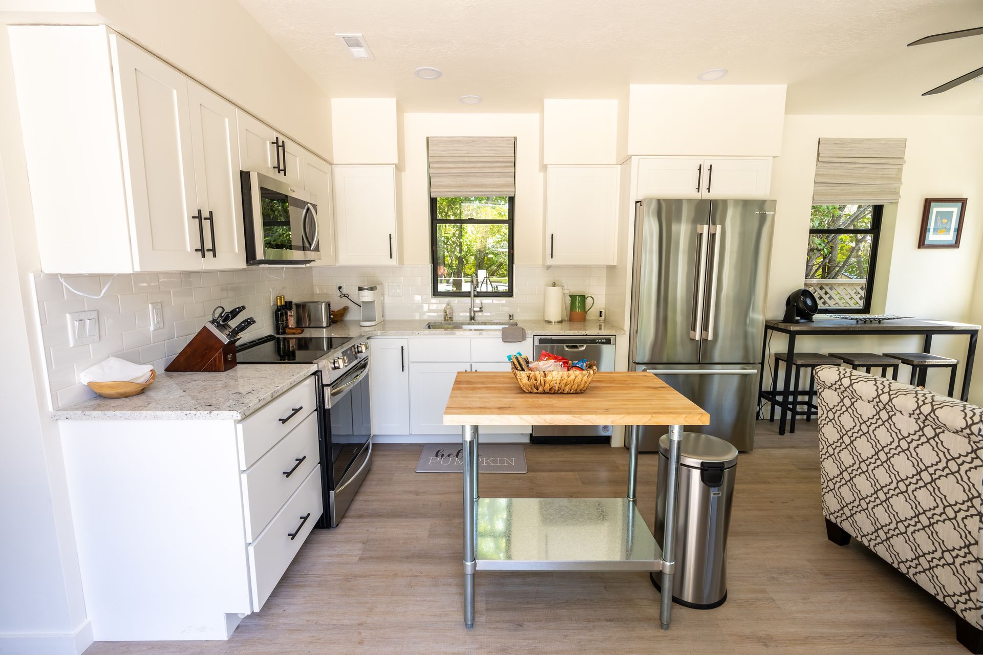 Perpetual Homes ADU: Bright white kitchen with stainless steel appliances, butcher block island, and light wood flooring.