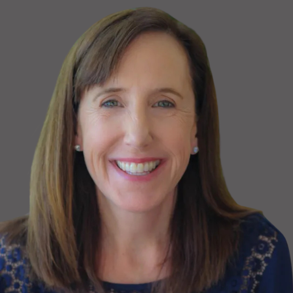 Beth McKnight of Perpetual Homes ADU. Smiling woman with shoulder-length brown hair, wearing a dark blue patterned top.