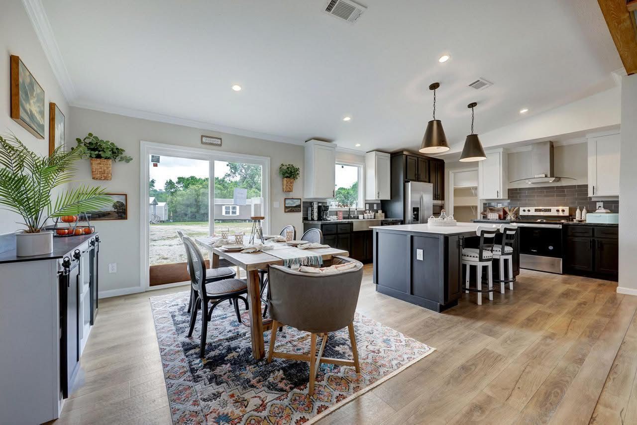 Modern open-plan kitchen and dining area with dark cabinets, island seating, and large windows
