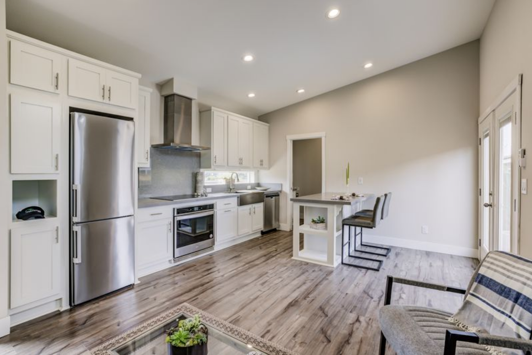 Perpetual Homes ADU: Modern kitchen with white cabinets, stainless steel appliances, and an open living concept.