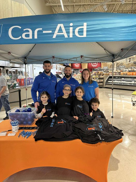 A group of people are standing under a car-aid tent in a store.