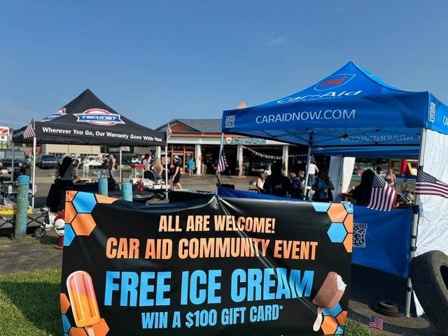 A car aid community event offering free ice cream.  Blue and orange tent with a sign that reads