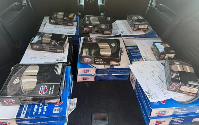 Car trunk filled with brake pads and rotors in boxes.