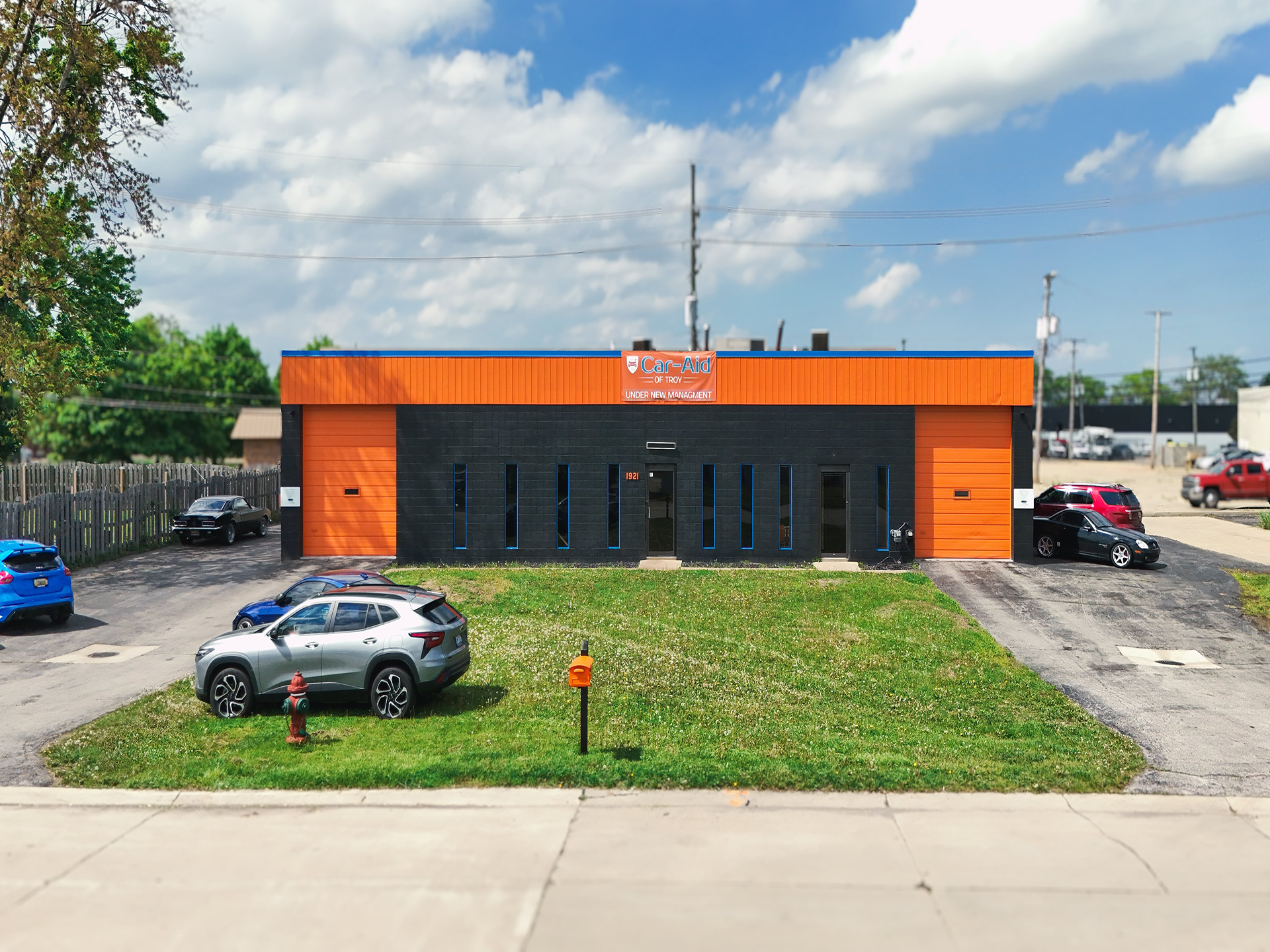 Three sports cars are parked in front of an orange building.