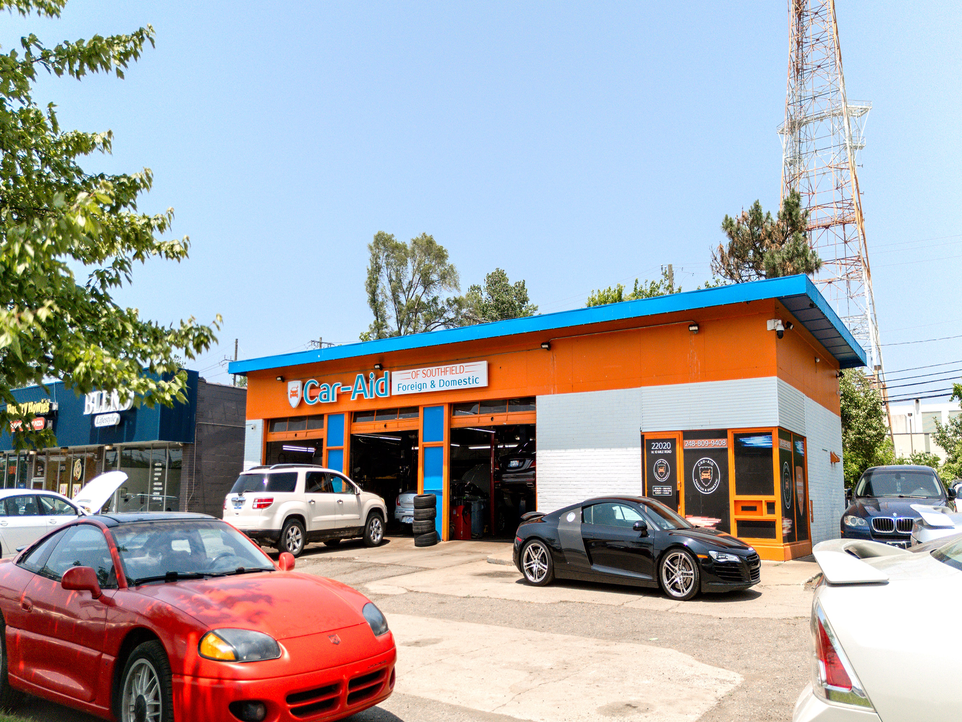 A row of cars are parked in front of a car dealership.