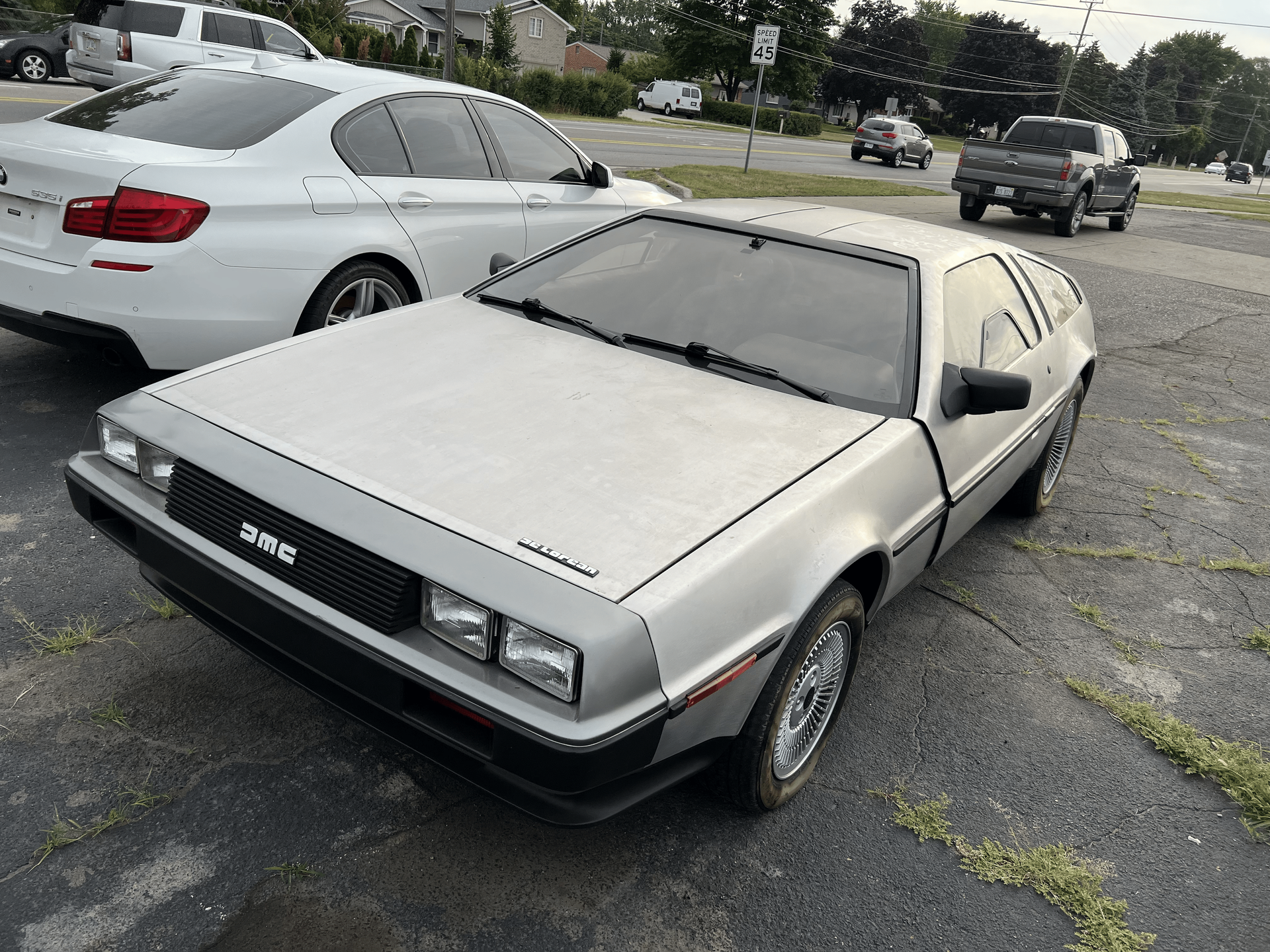 A silver car is parked next to a white car in a parking lot.