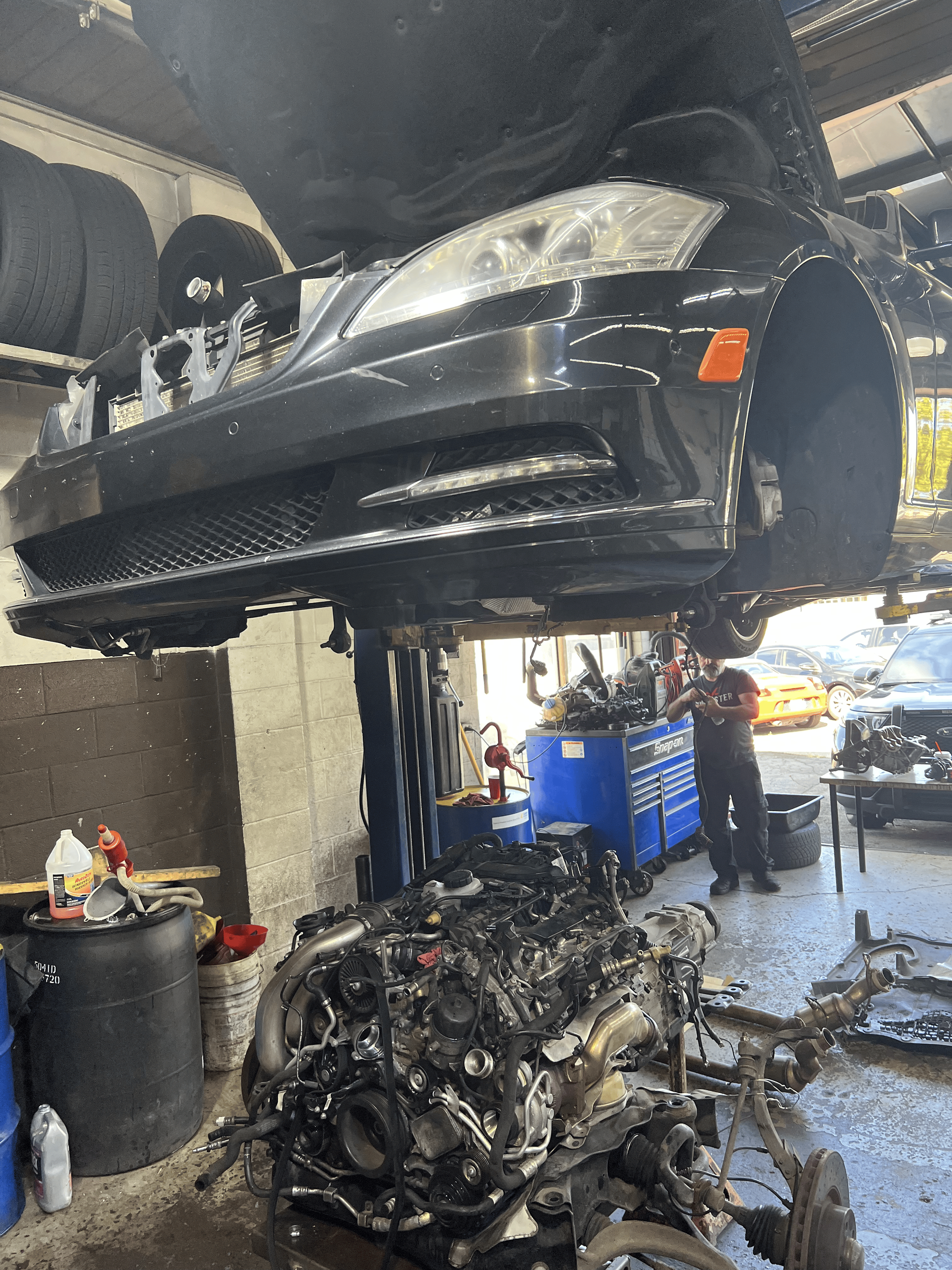 A car is being repaired in a garage with the hood up.
