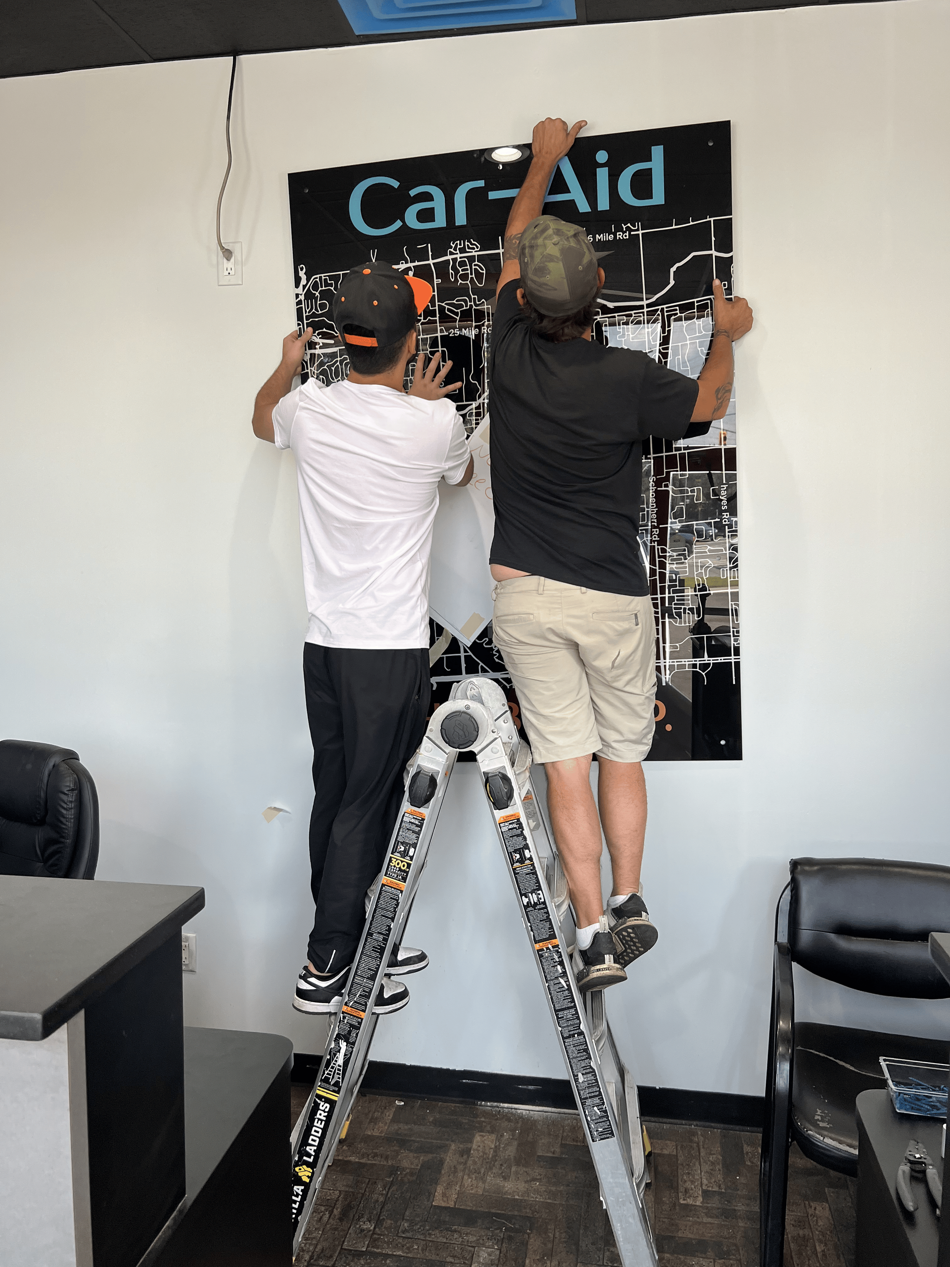 Two men are working on a sign that says car aid