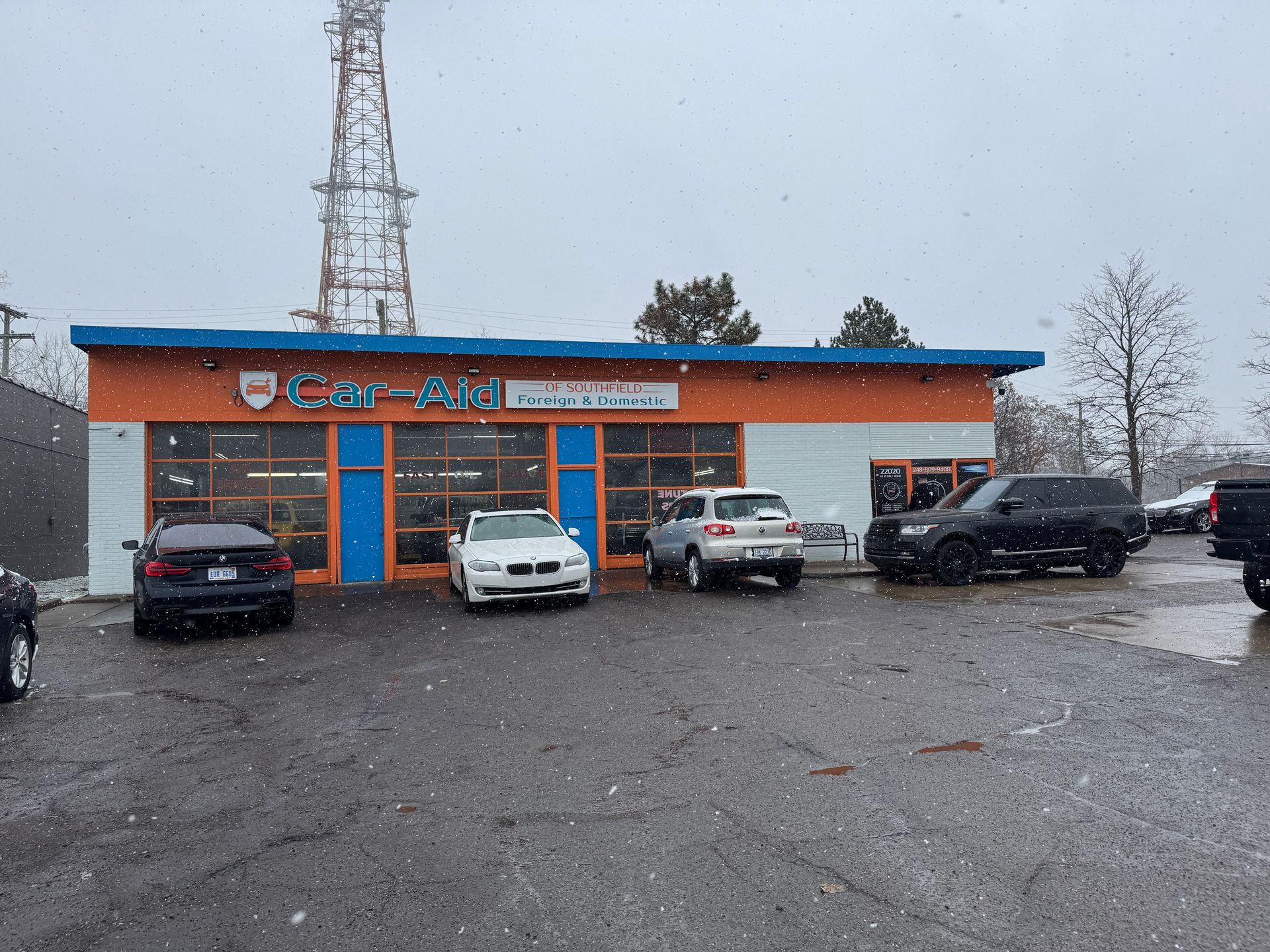 A row of cars are parked in front of a car dealership.