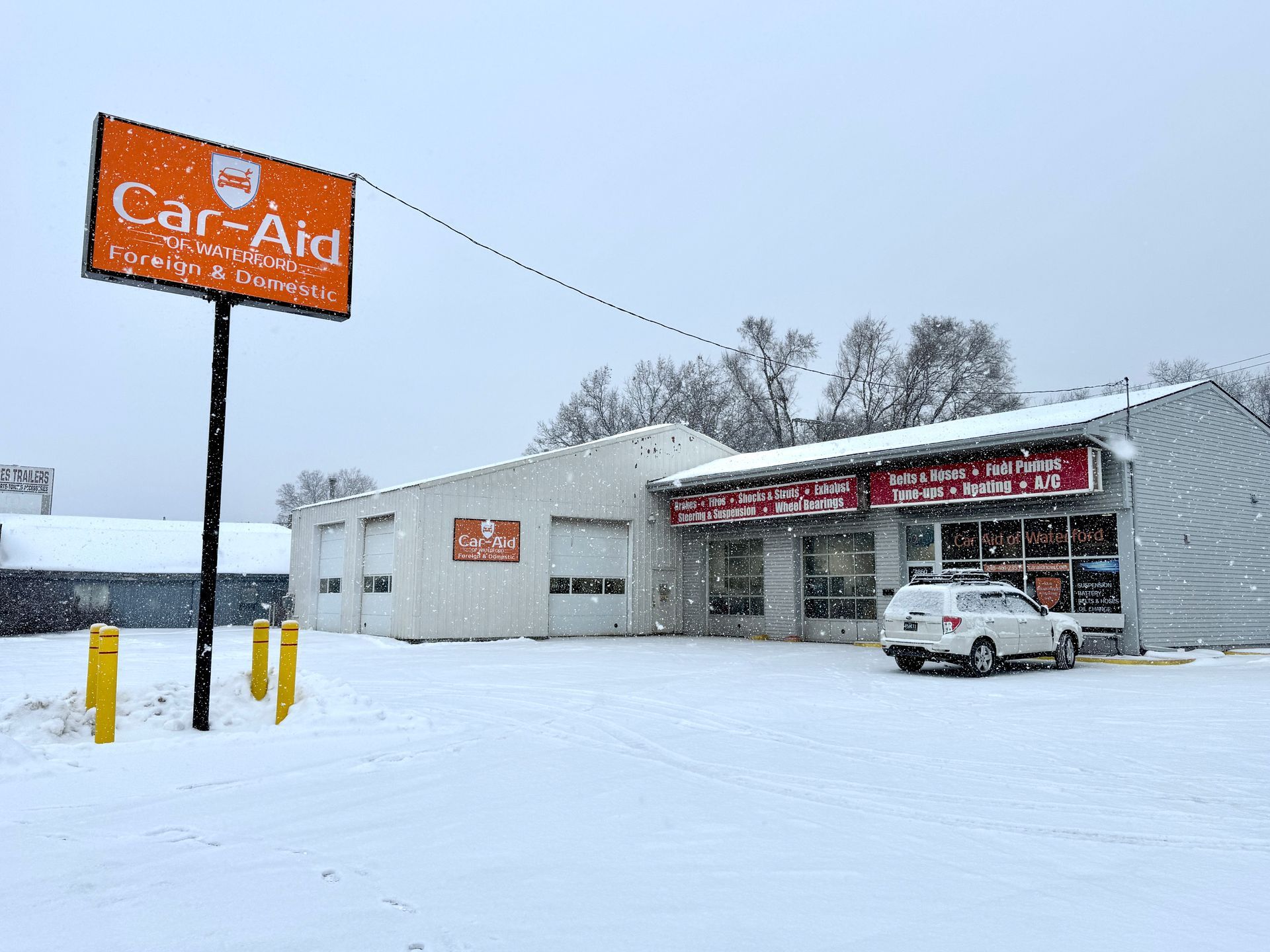 A car is parked in front of a car aid store in the snow.