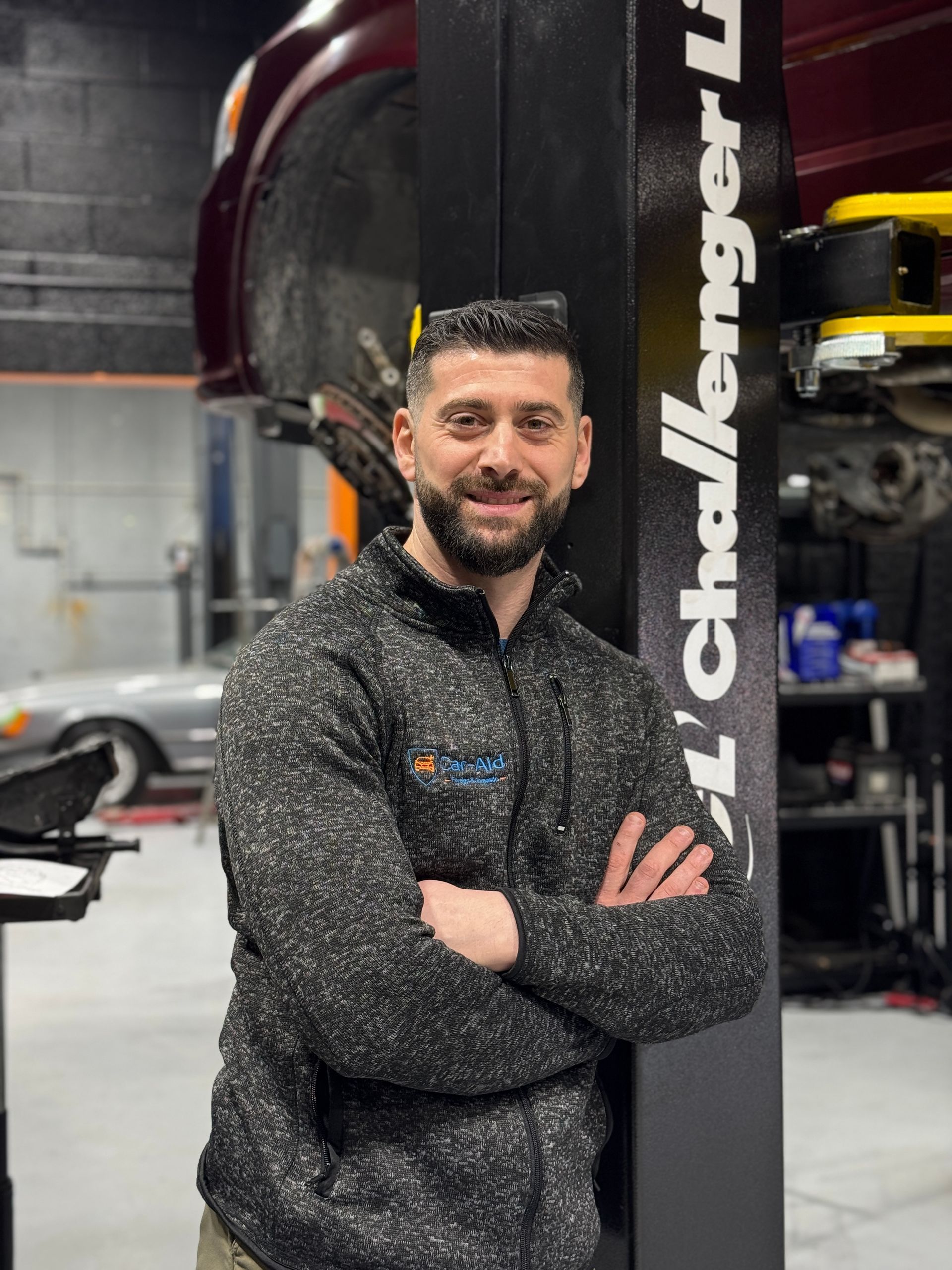 A man is standing in front of a challenger lift in a garage.