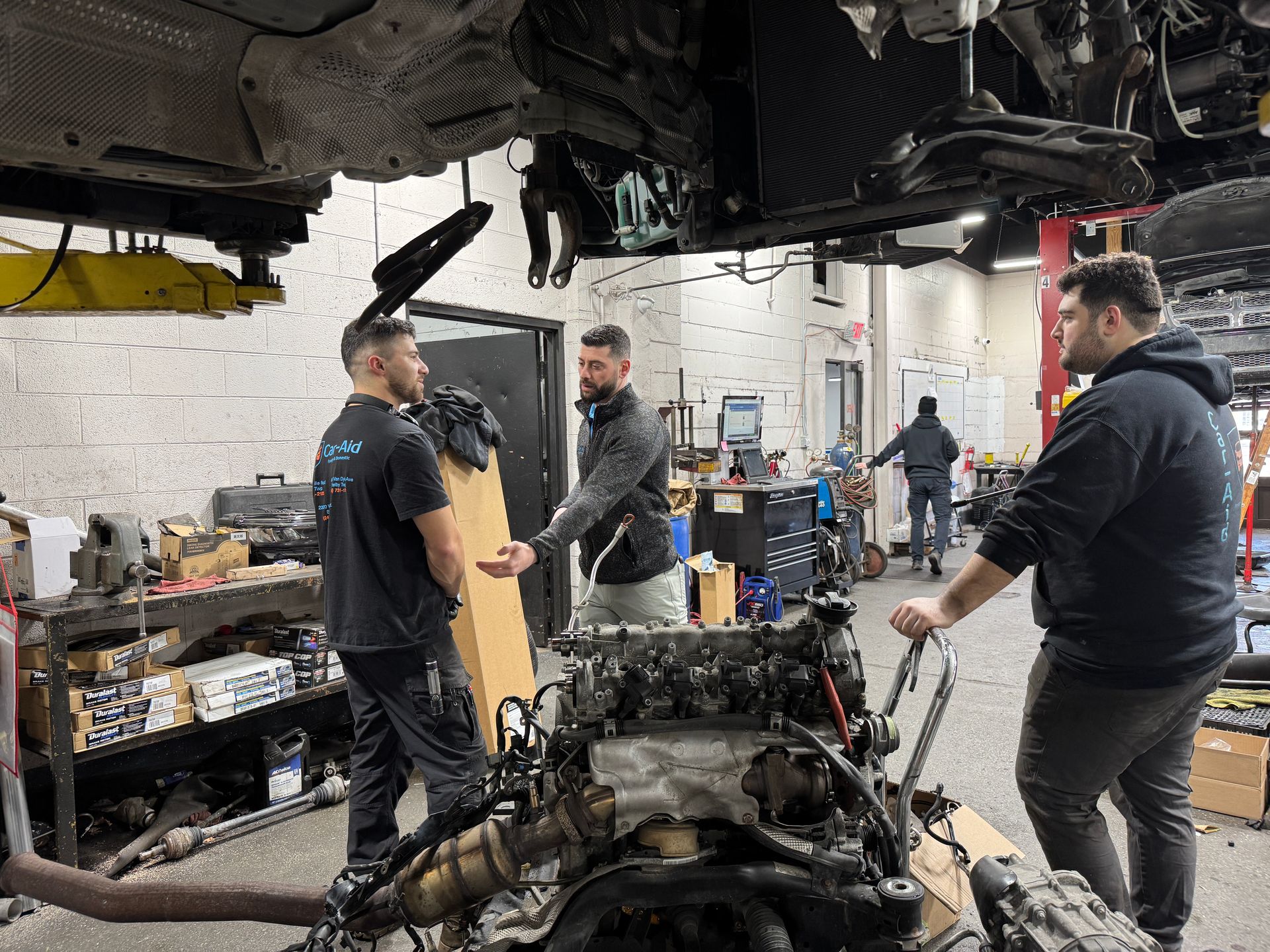 A group of men are working on a car engine in a garage.