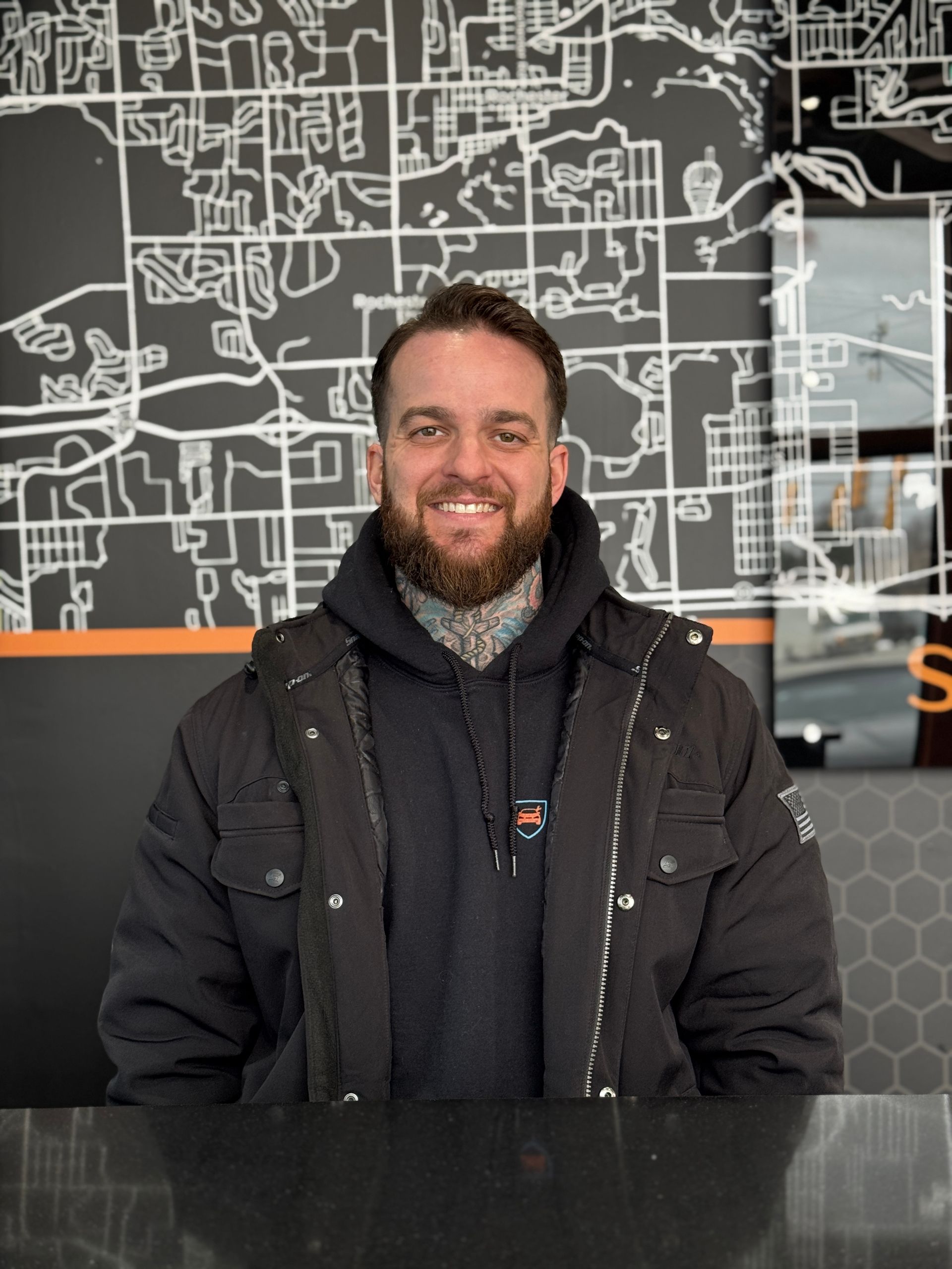 A man with a beard is sitting at a counter in front of a map.