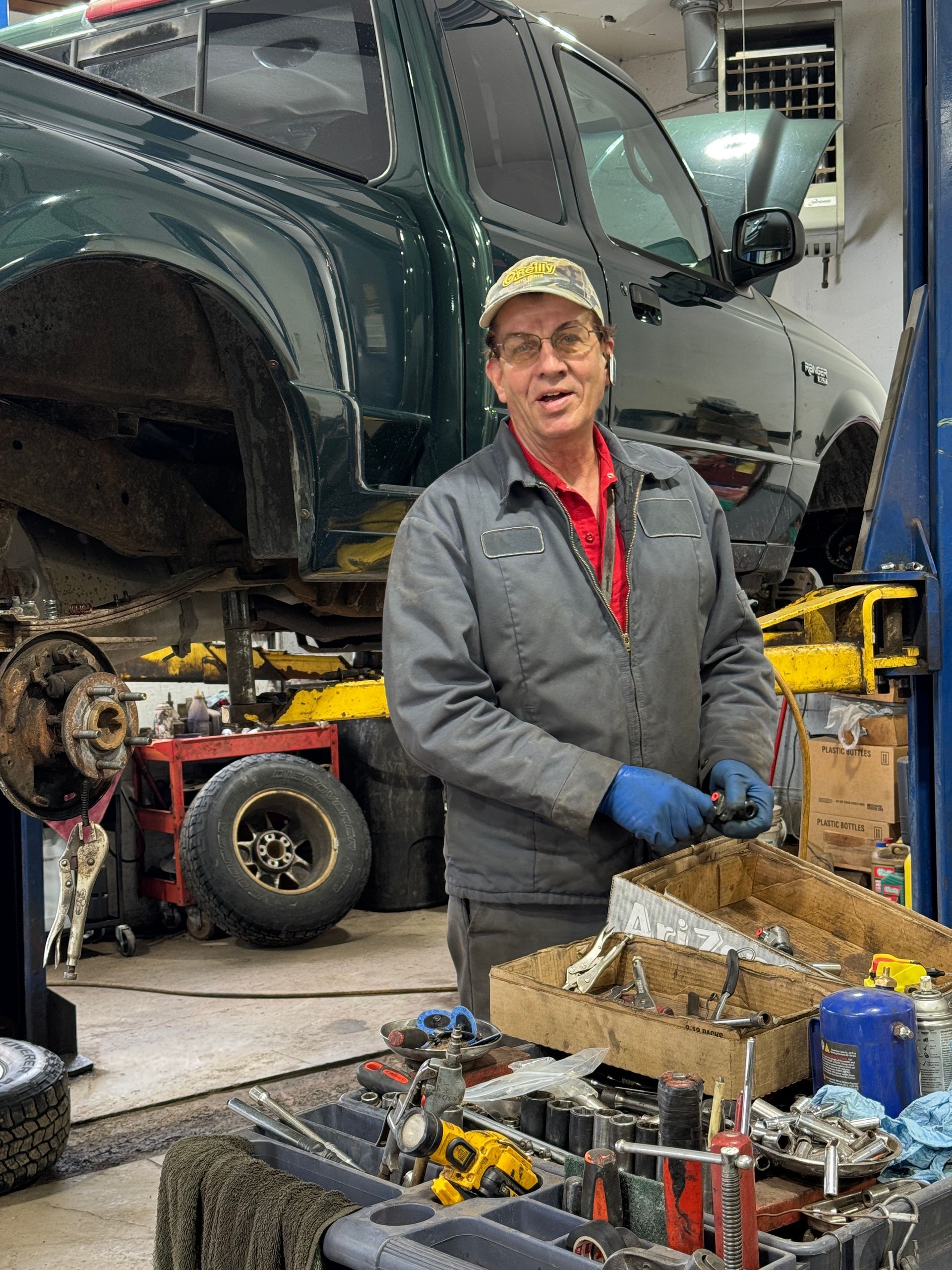 A man is standing in front of a truck in a garage.