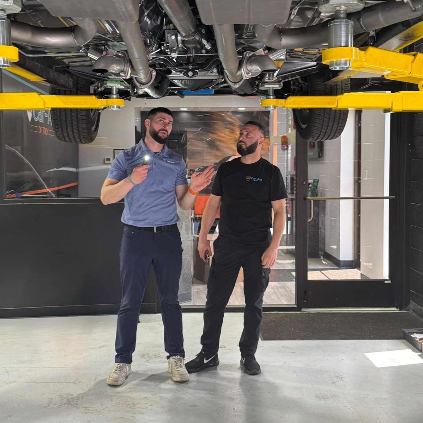 guy standing underneath car to fix it