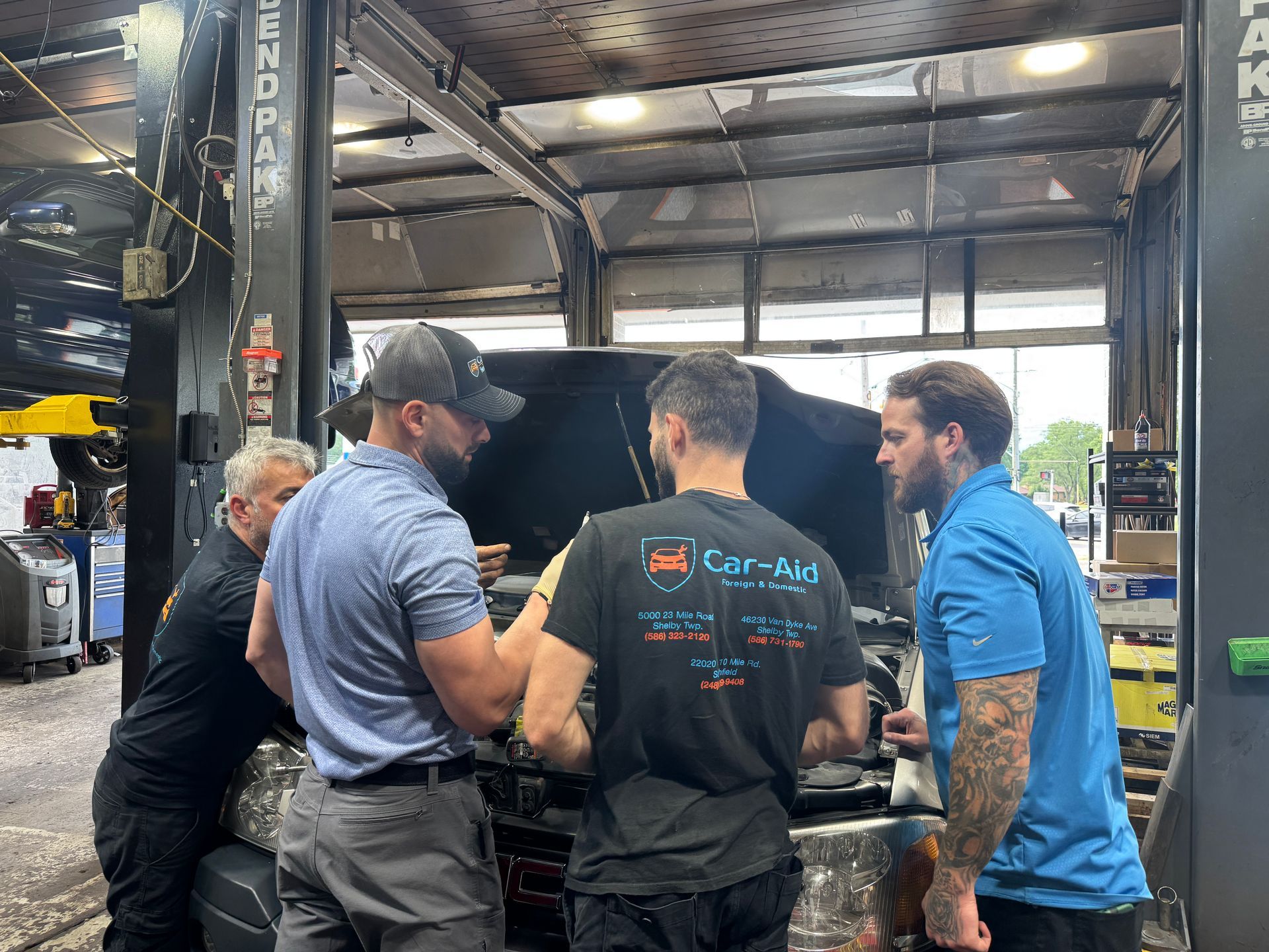 Four mechanics working on a vehicle at Car Aid
