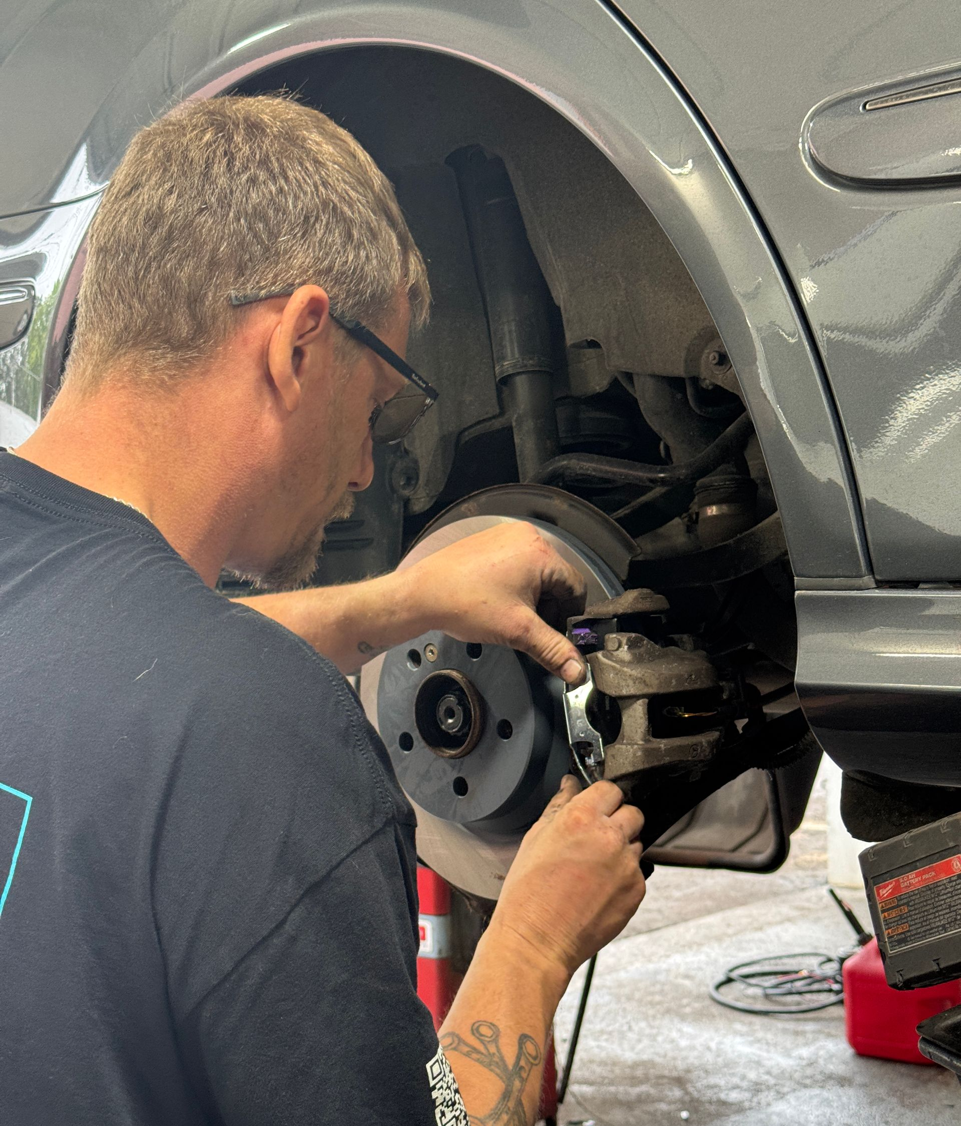 A man is working under the hood of a car.