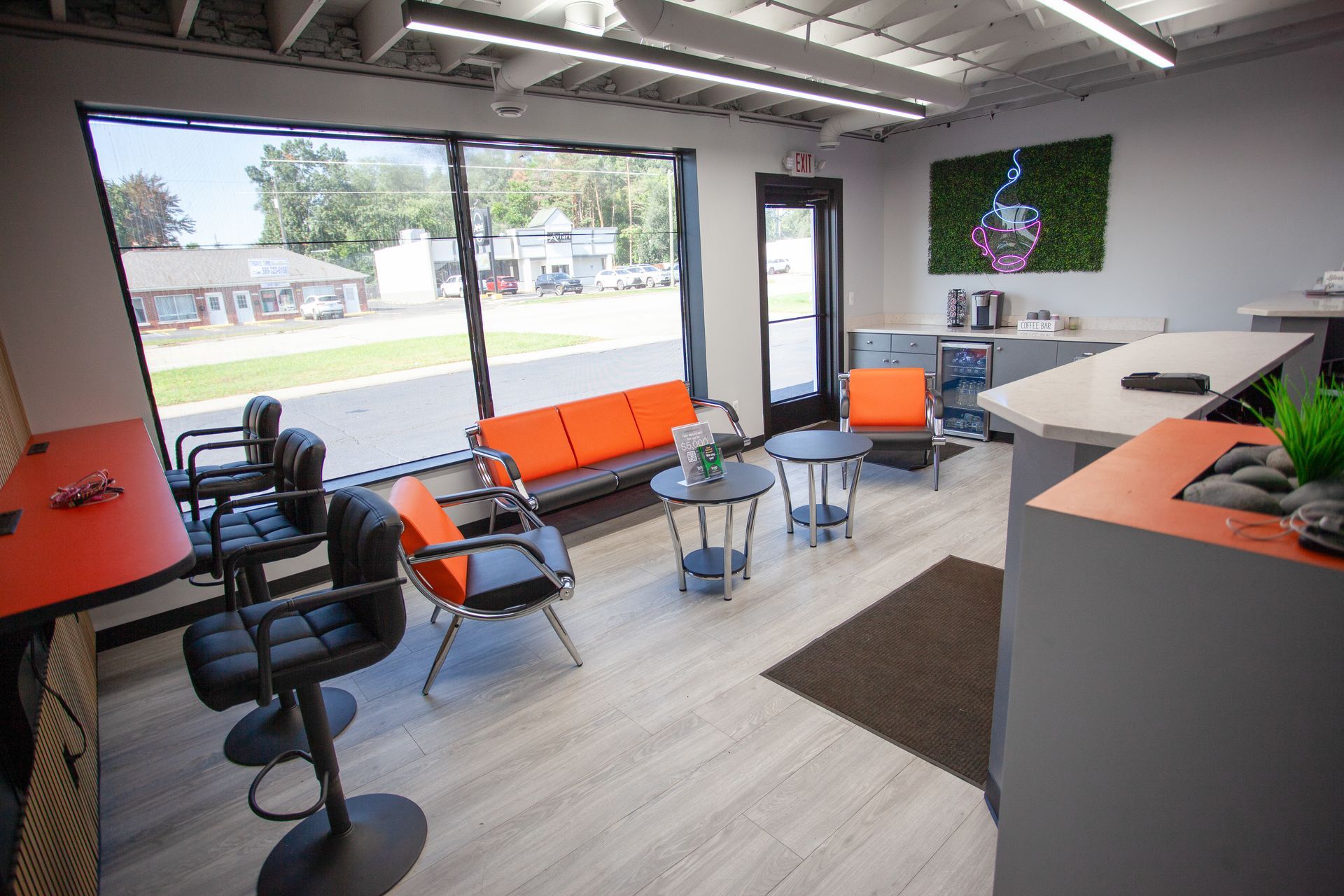 A waiting room with a couch , chairs , tables and a counter.