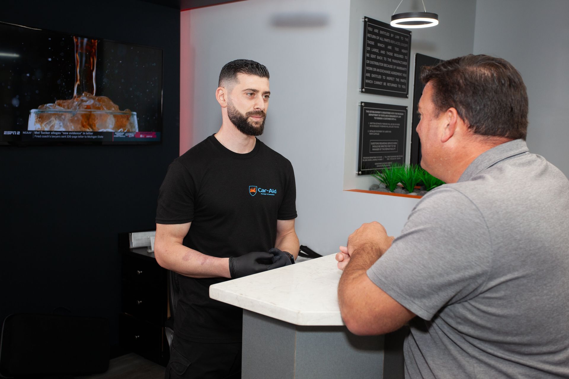 A man is standing at a counter talking to another man.