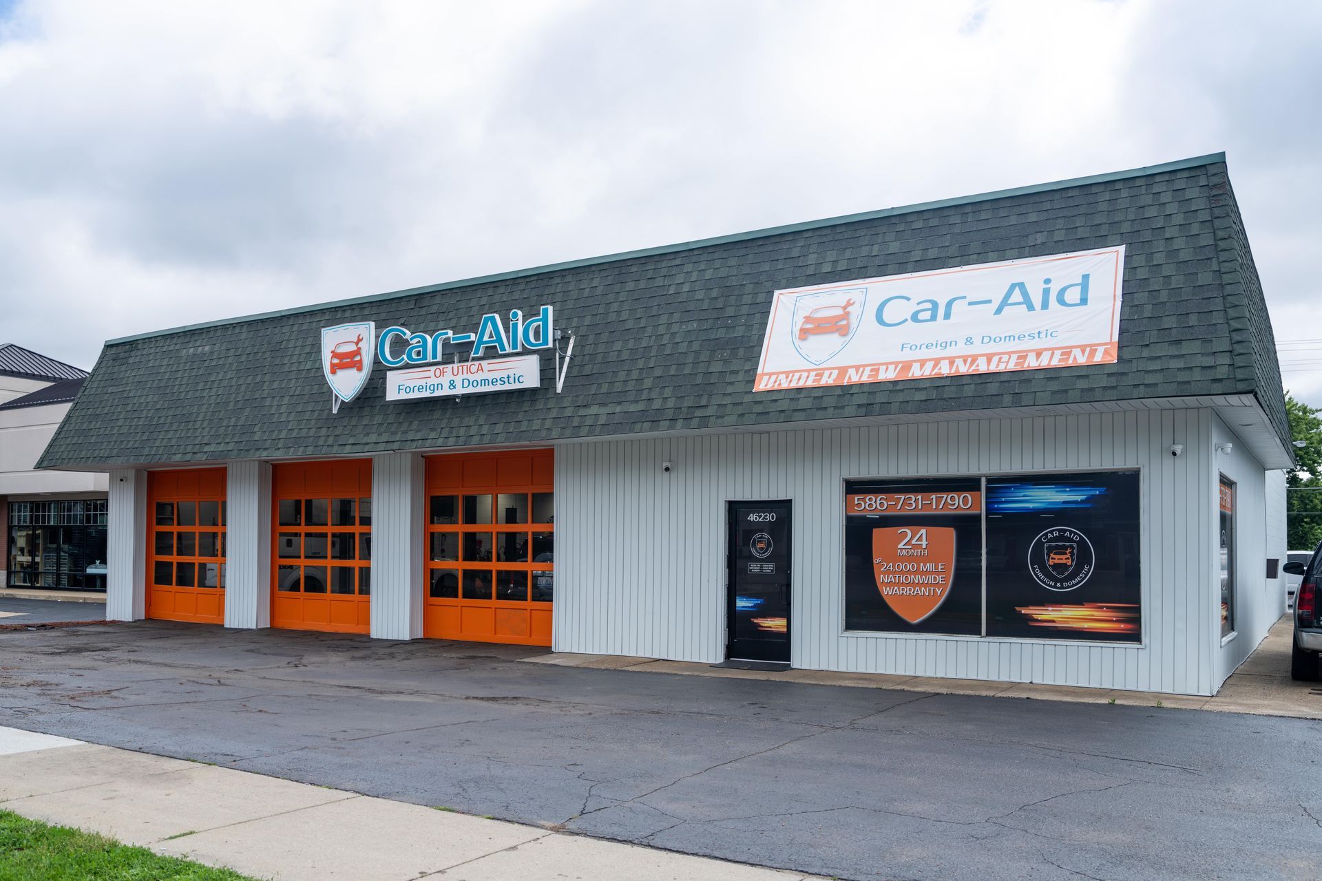 A white building with orange garage doors and a sign that says car-aid
