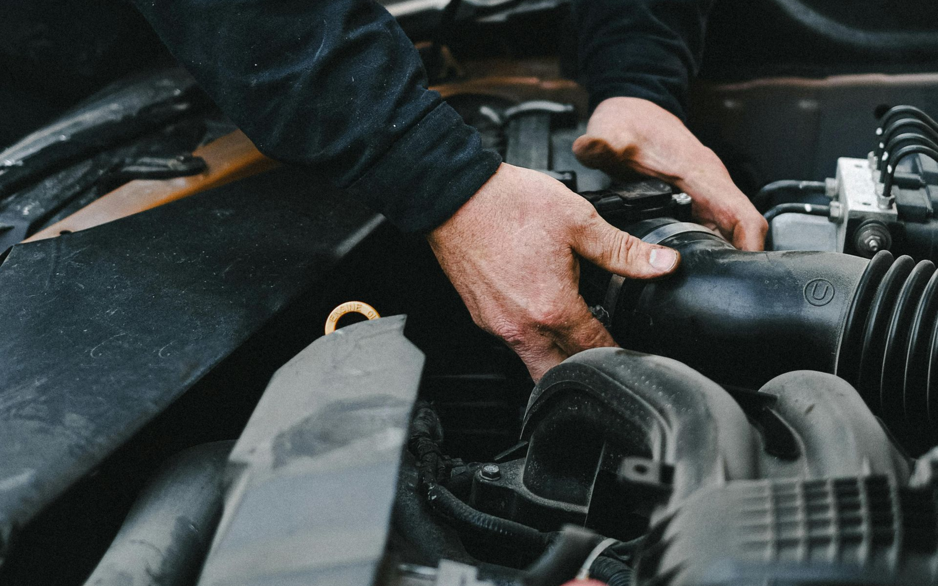 Hands working on car engine.