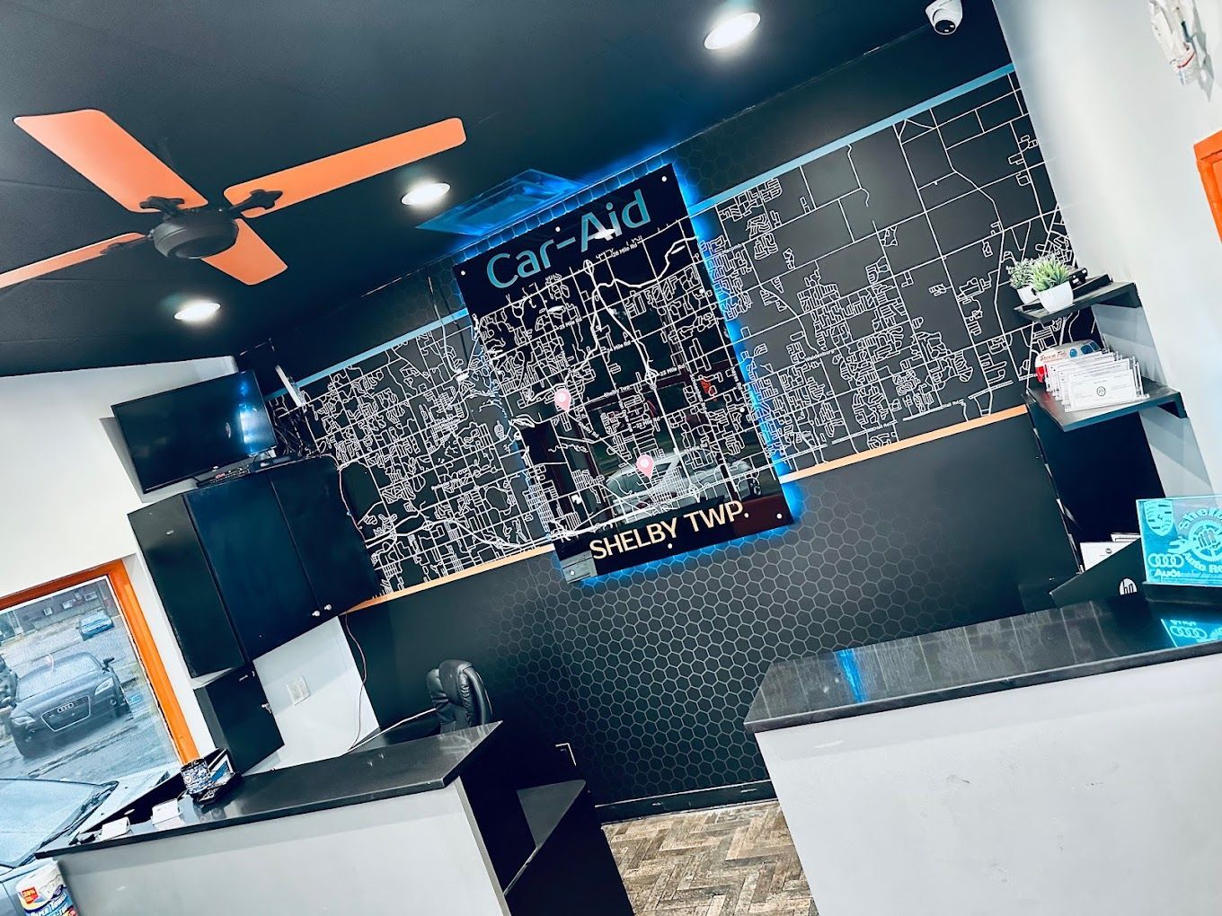 A ceiling fan is hanging from the ceiling of a car repair shop.