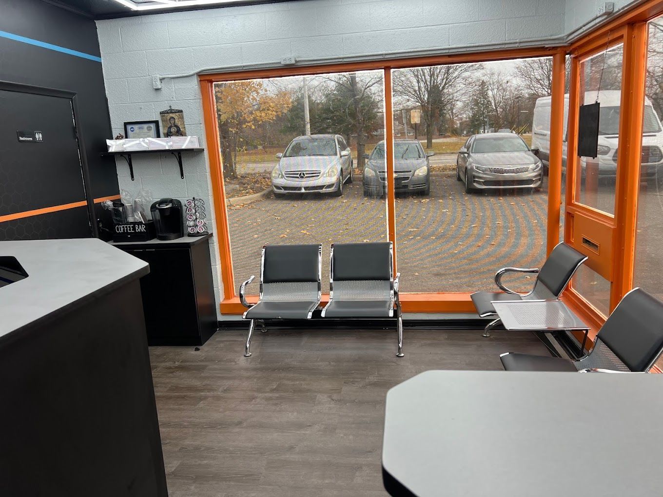 A waiting room with chairs and a large window with cars parked in the background.