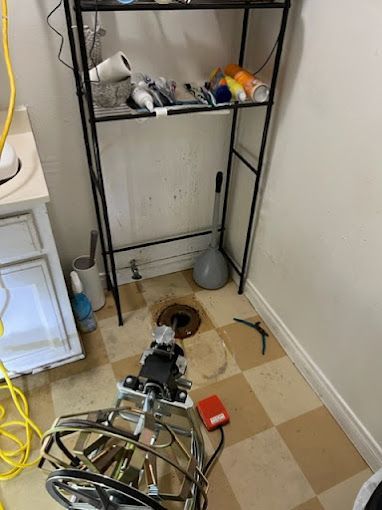 A plumber is working on a drain in a bathroom.