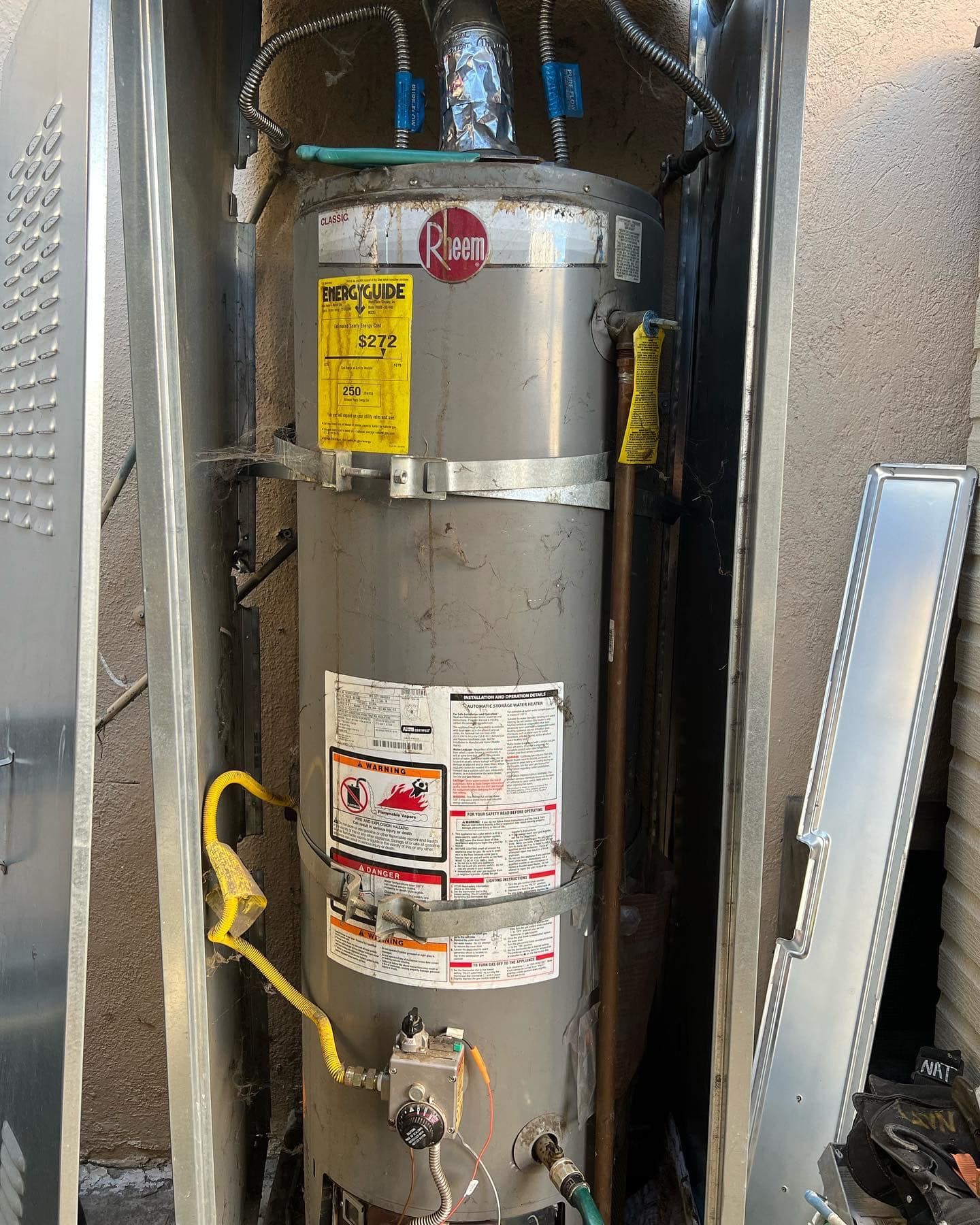 A gray water heater is sitting inside of a metal box.